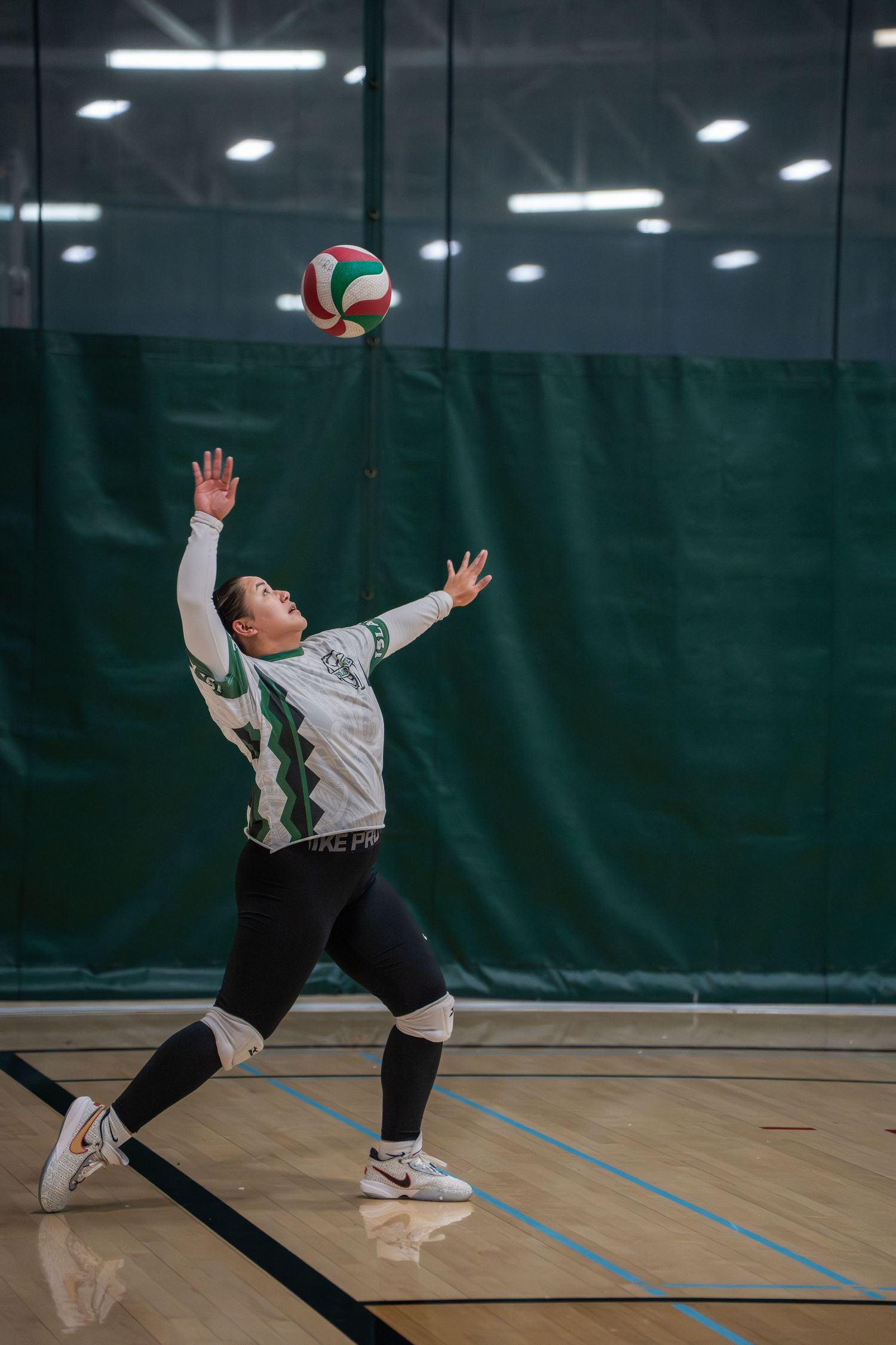 Volleyball player executing a diving save on a gymnasium floor during a match.