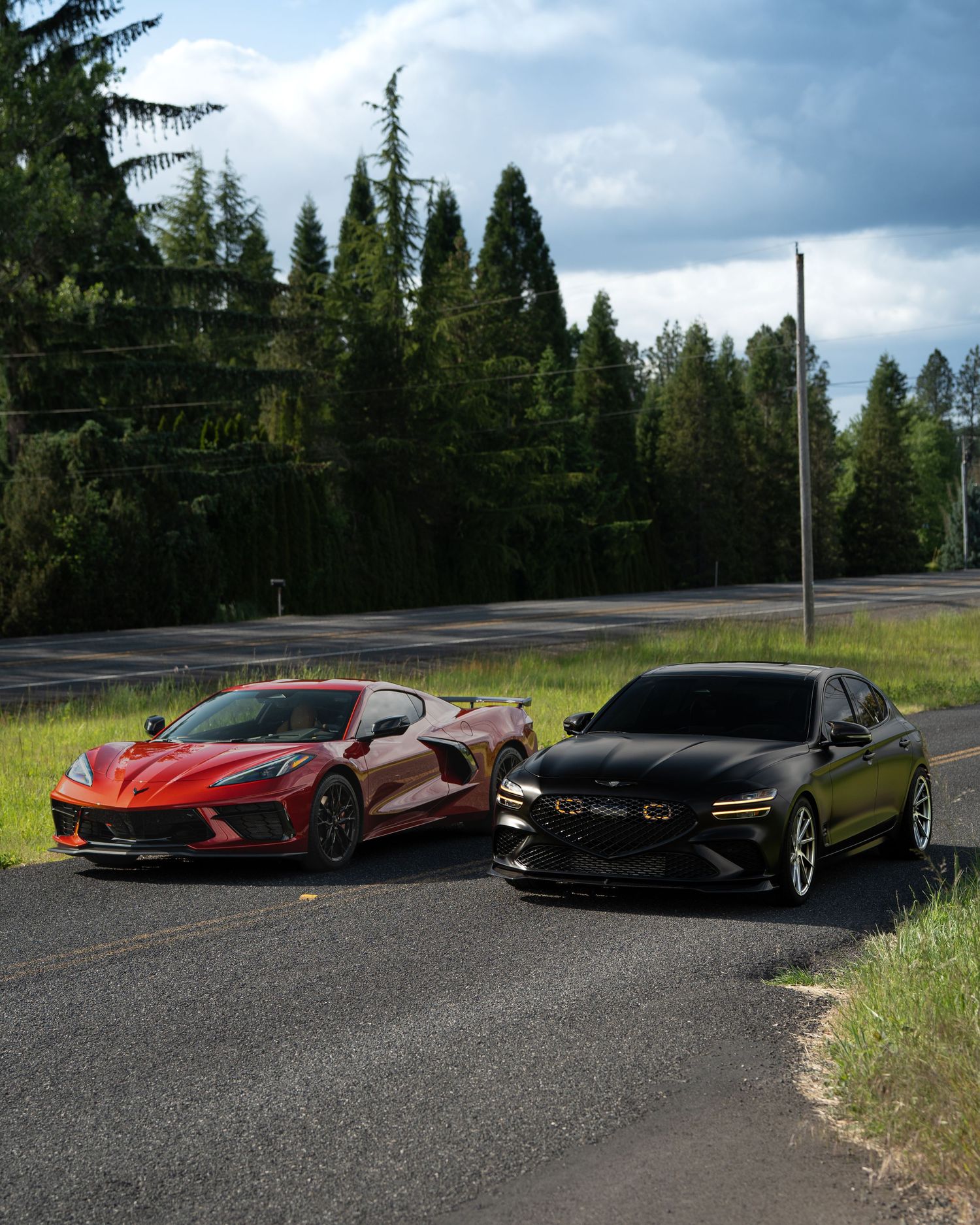 Multiple Genesis luxury vehicles parked together on a rural road with evergreen trees in the background.