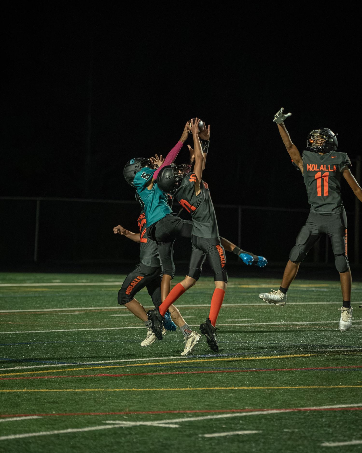 Athletes demonstrate agility drills while wearing teal and black uniforms on the football field.