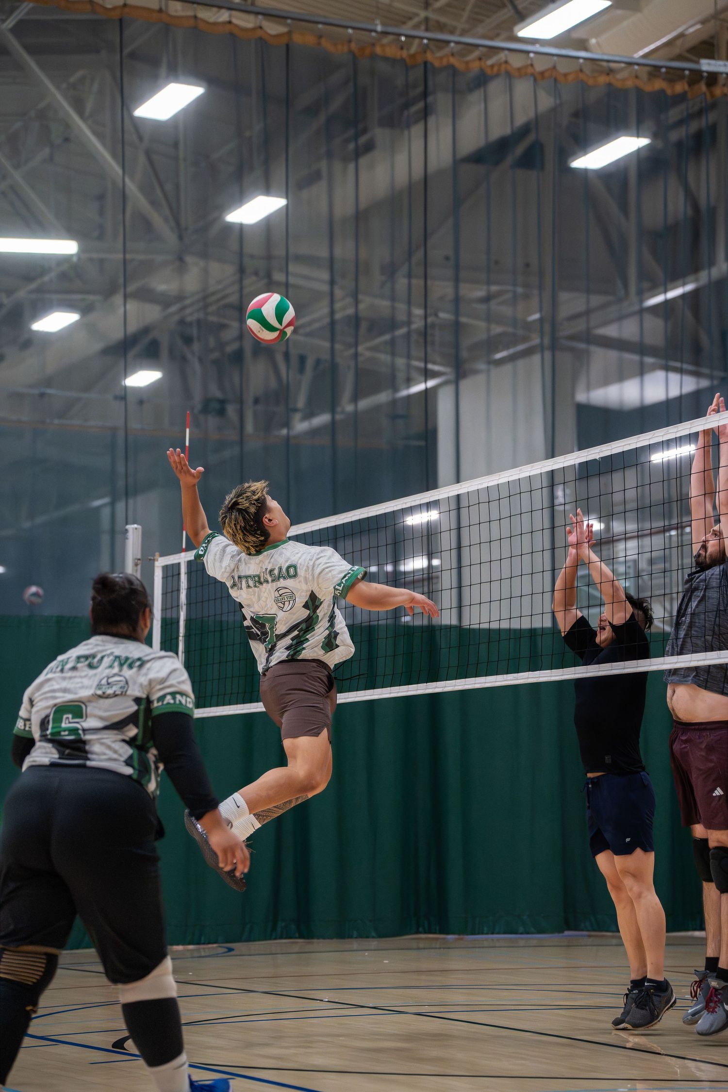 Players executing defensive moves during an indoor volleyball game.
