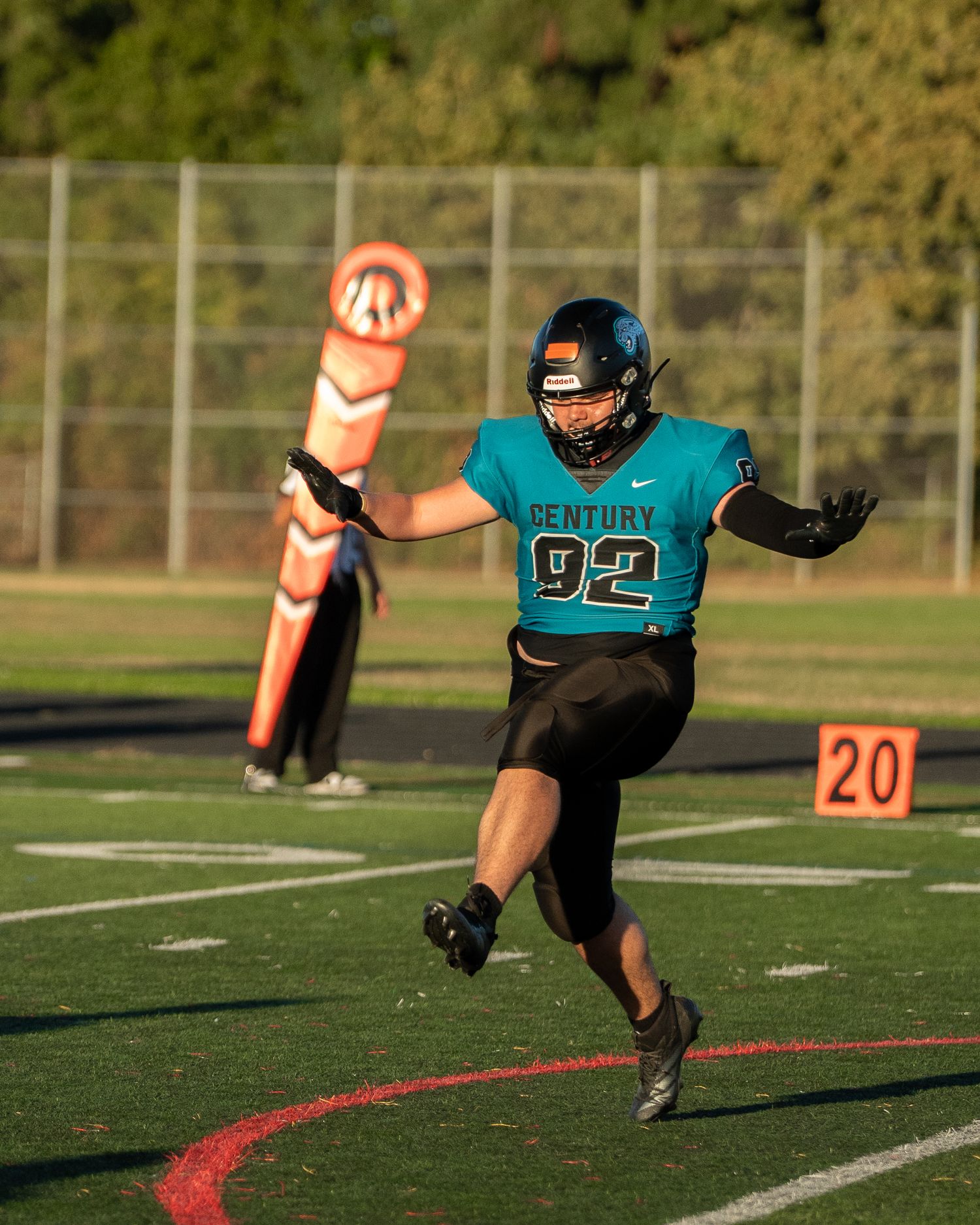 Football player in teal and black uniform executes a diving play on the field.