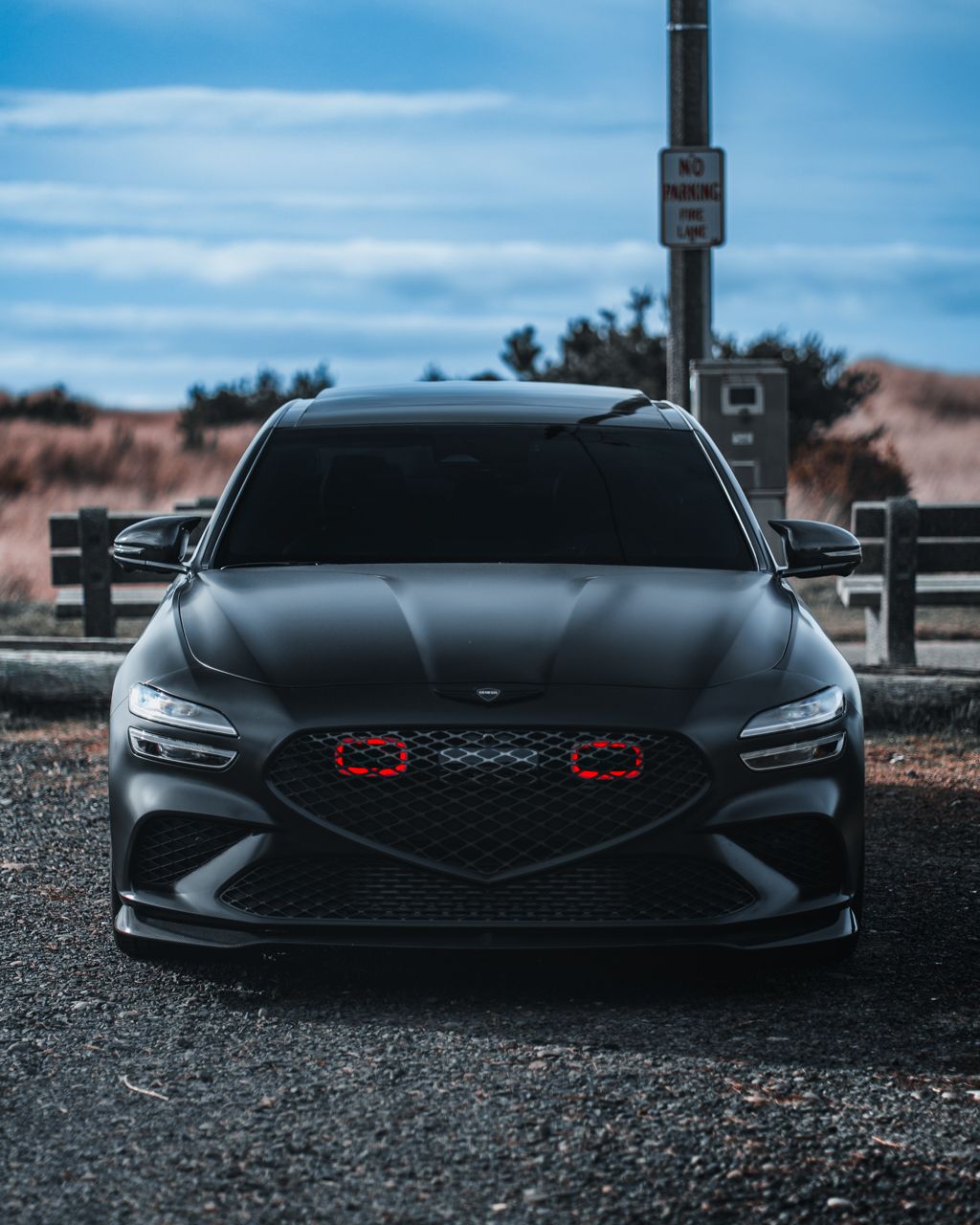 Front view of an aggressive black sports car with glowing red accents in the grille.