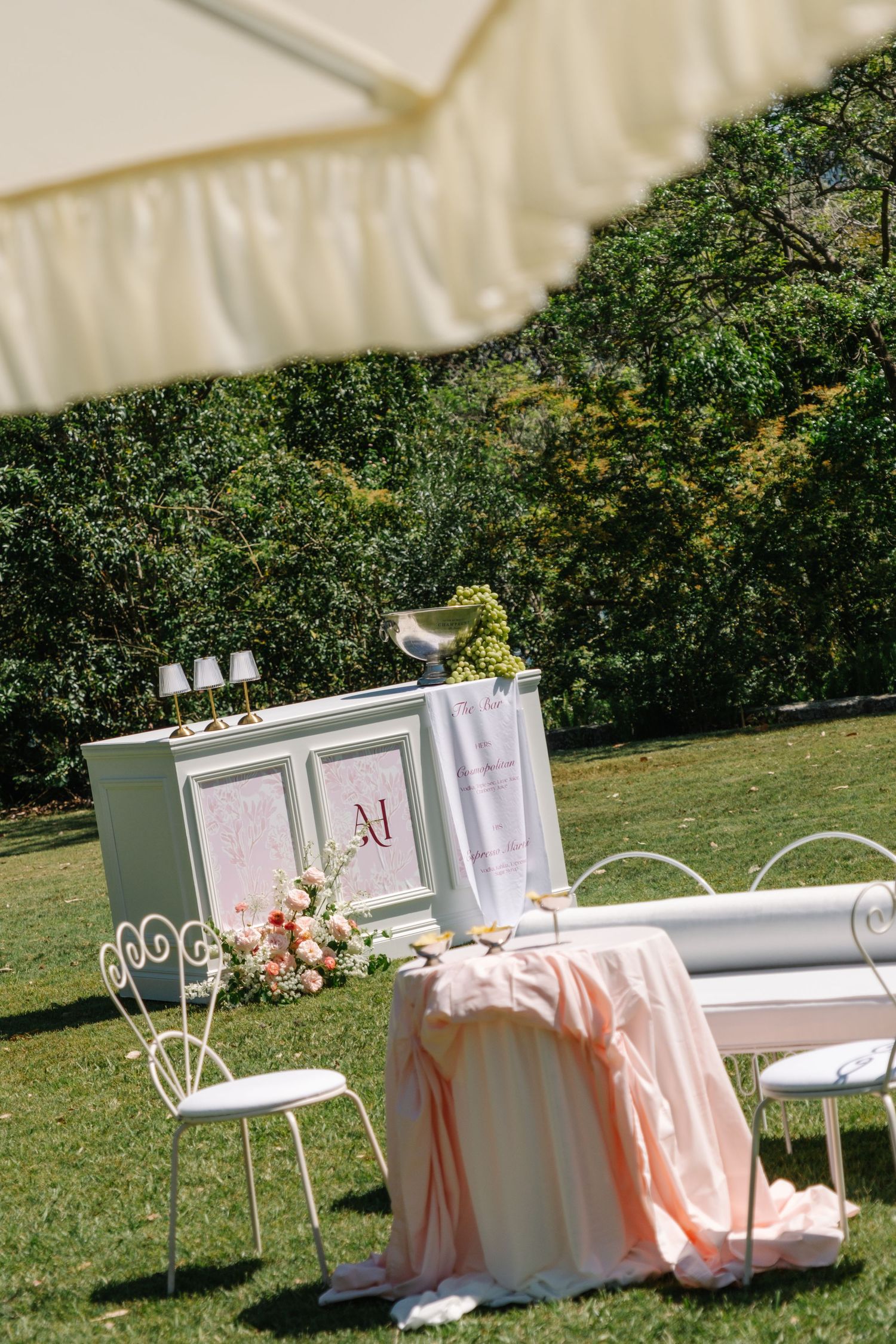 White chairs and tables with peach-colored linens set up for an outdoor garden event under a sunny sky.
