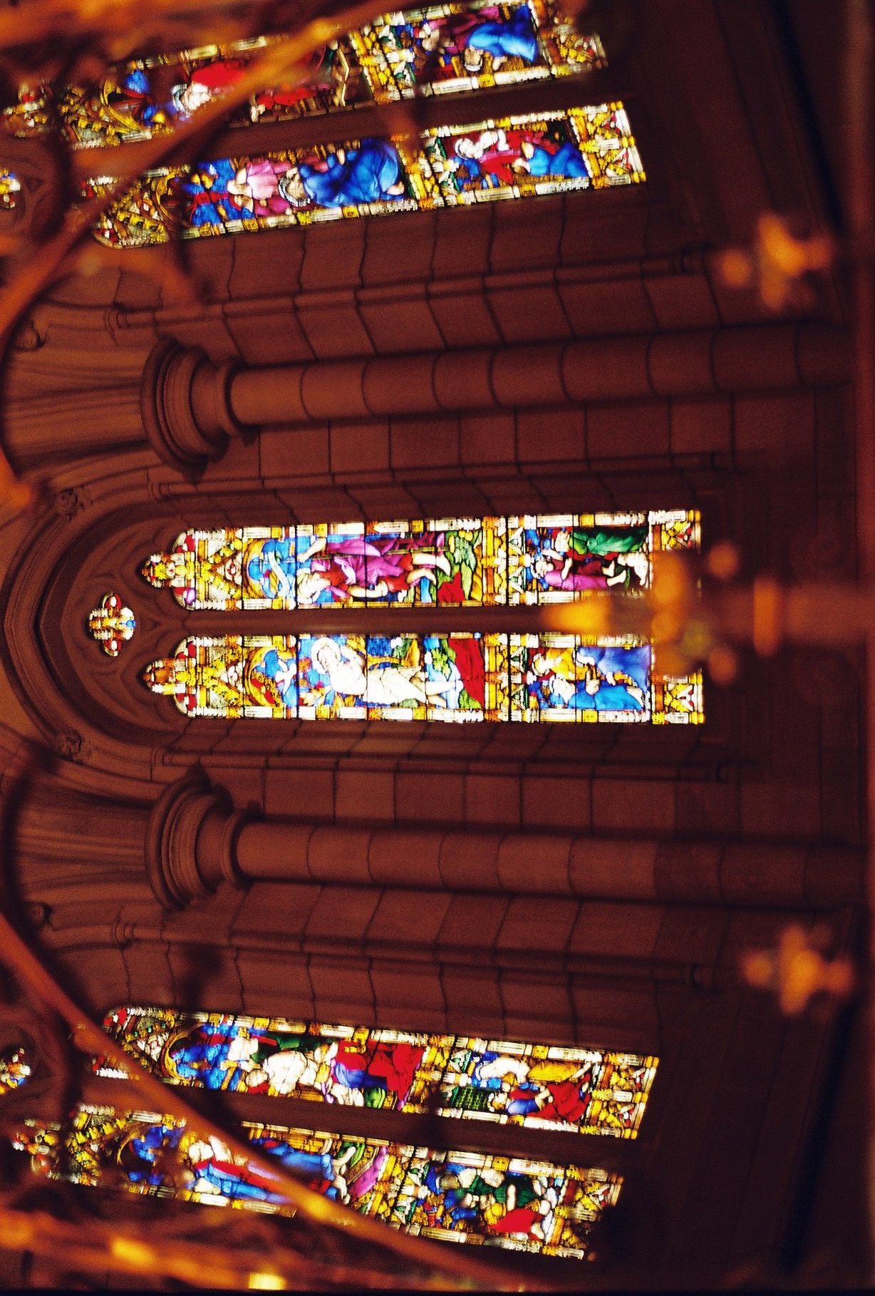 Colorful stained glass windows in a church with gothic architecture illuminated in warm lighting.