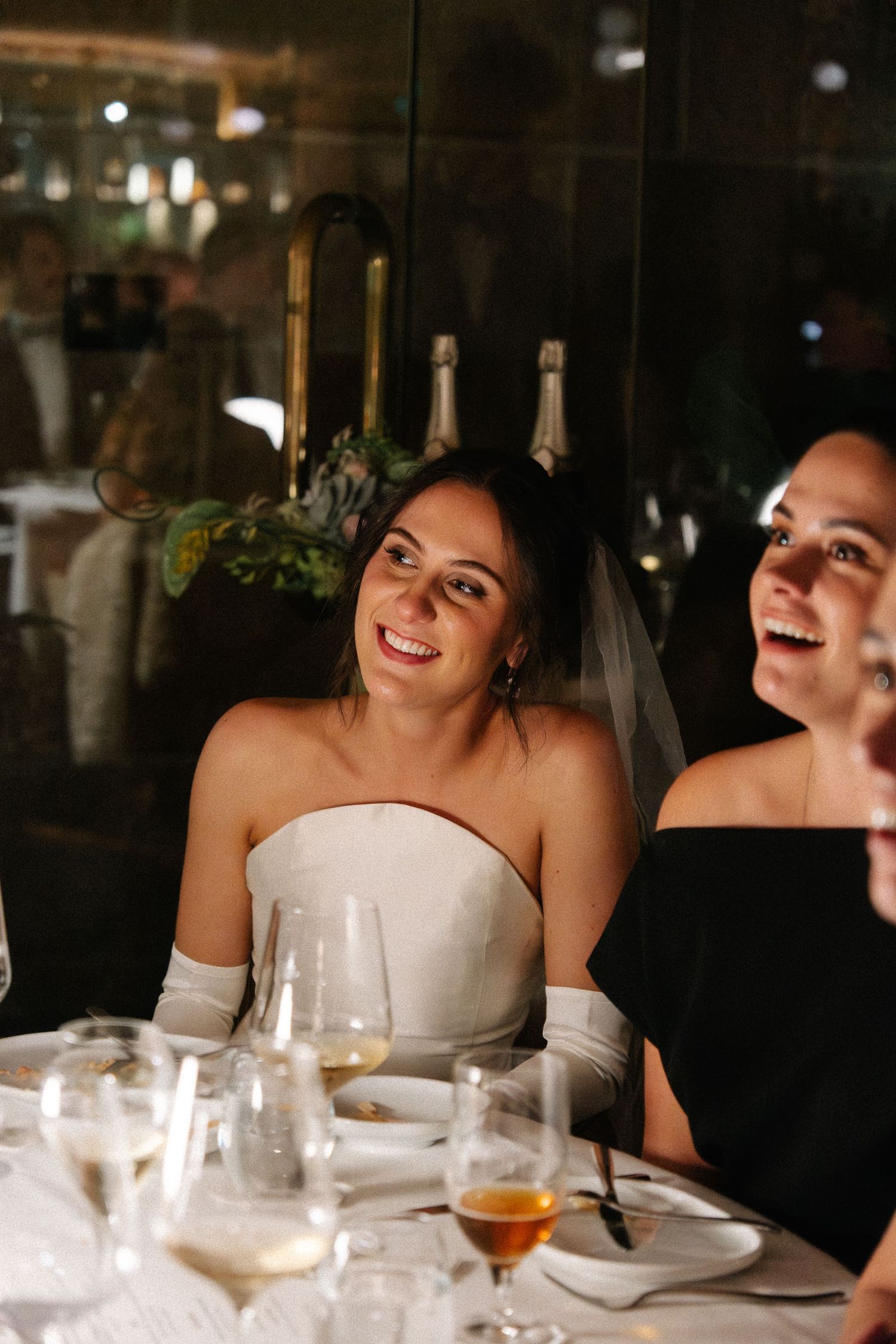 Wedding party members share laughter and smiles during an elegant evening reception dinner.