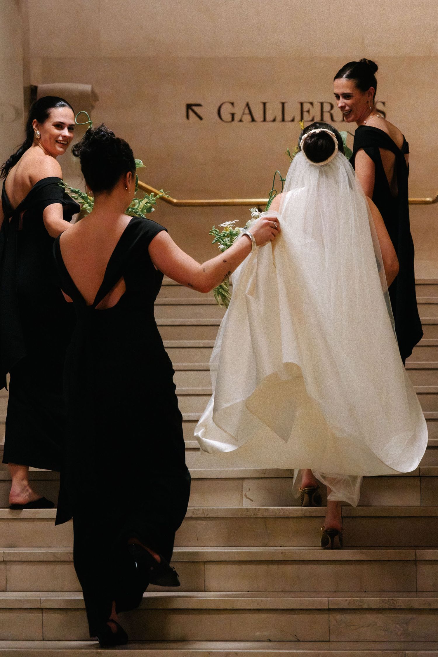 A sequence of artistic wedding photos showing a couple in black and white attire descending marble stairs.