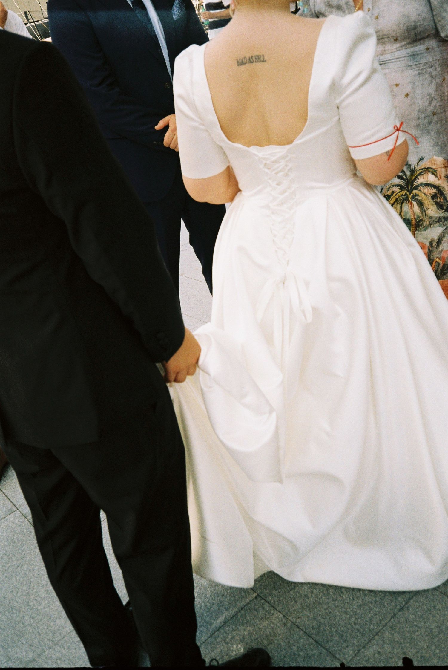 Close-up details of a white wedding dress with corset-style lacing and elegant fabric gathered at the back.