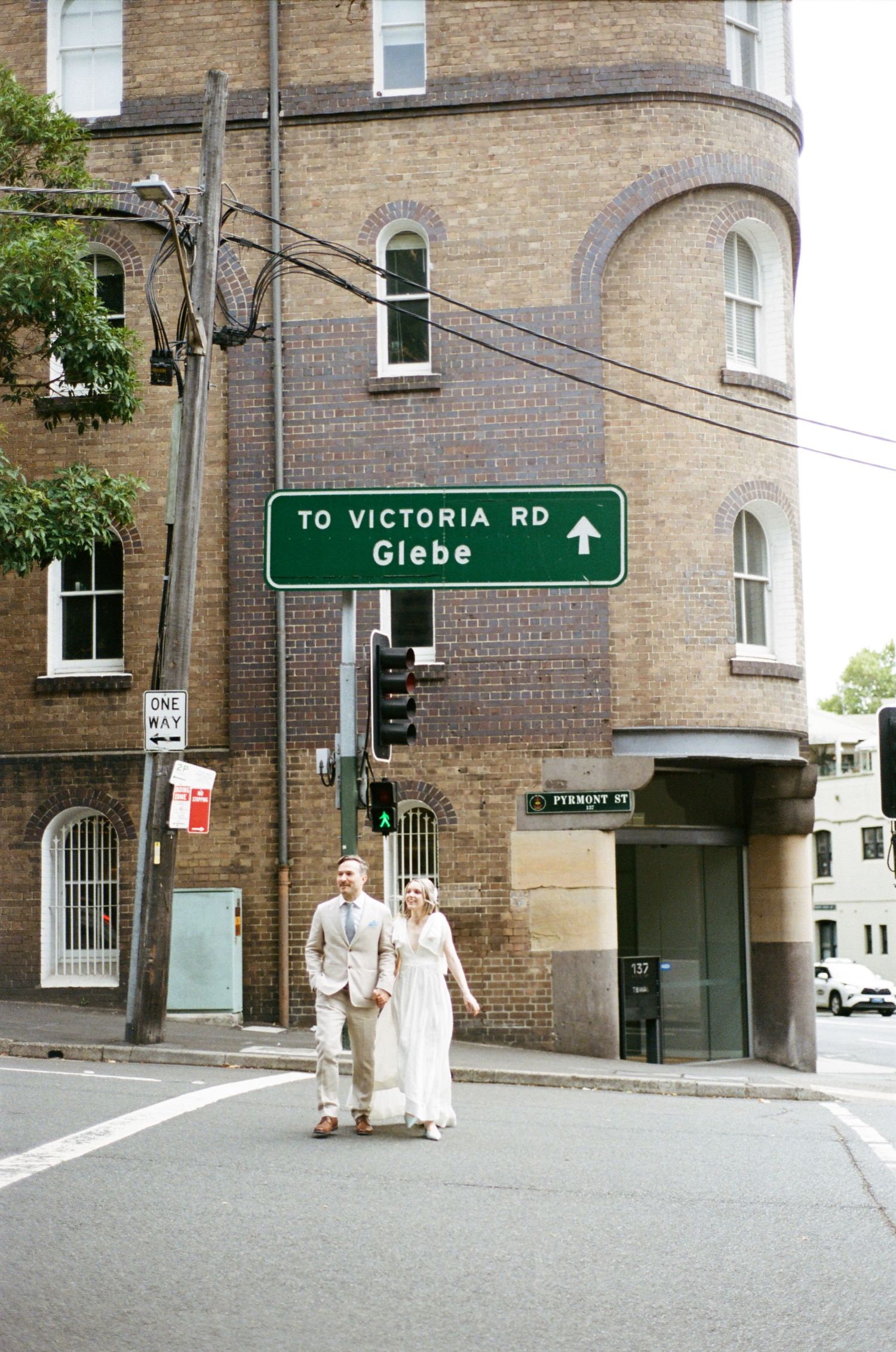 Historic brick building entrance with curved archway and street sign pointing to Victoria Road Glebe.