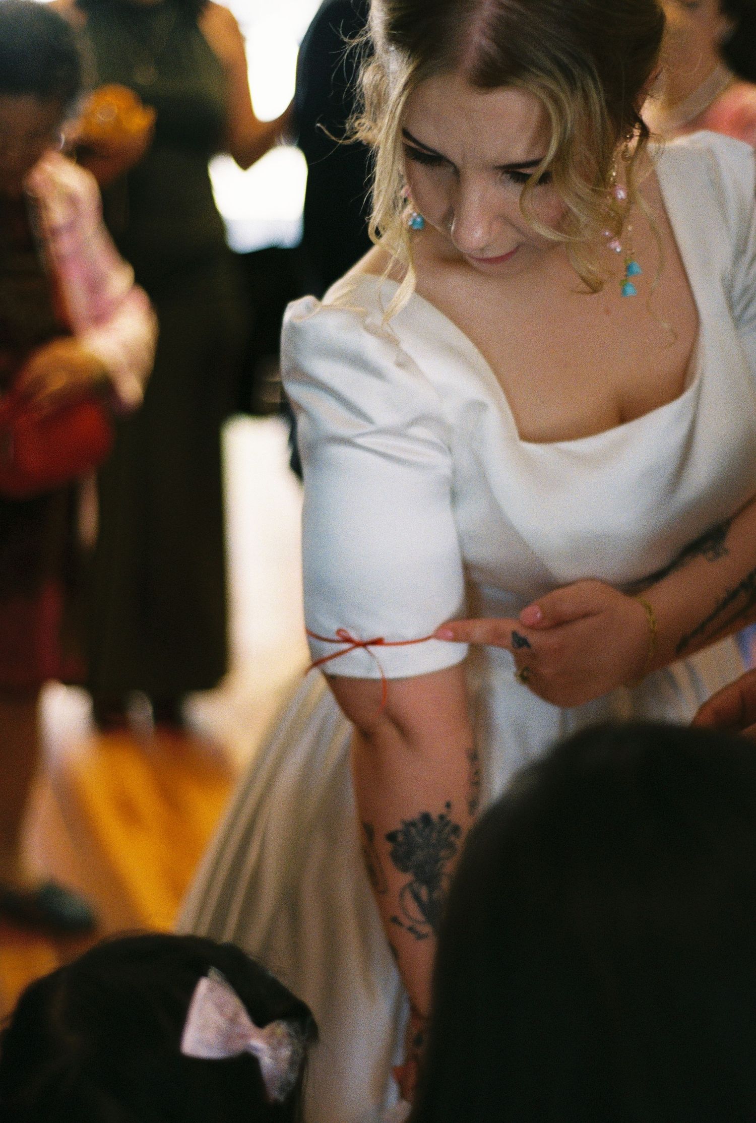 Close-up view of a bride's white dress being adjusted during a wedding ceremony.
