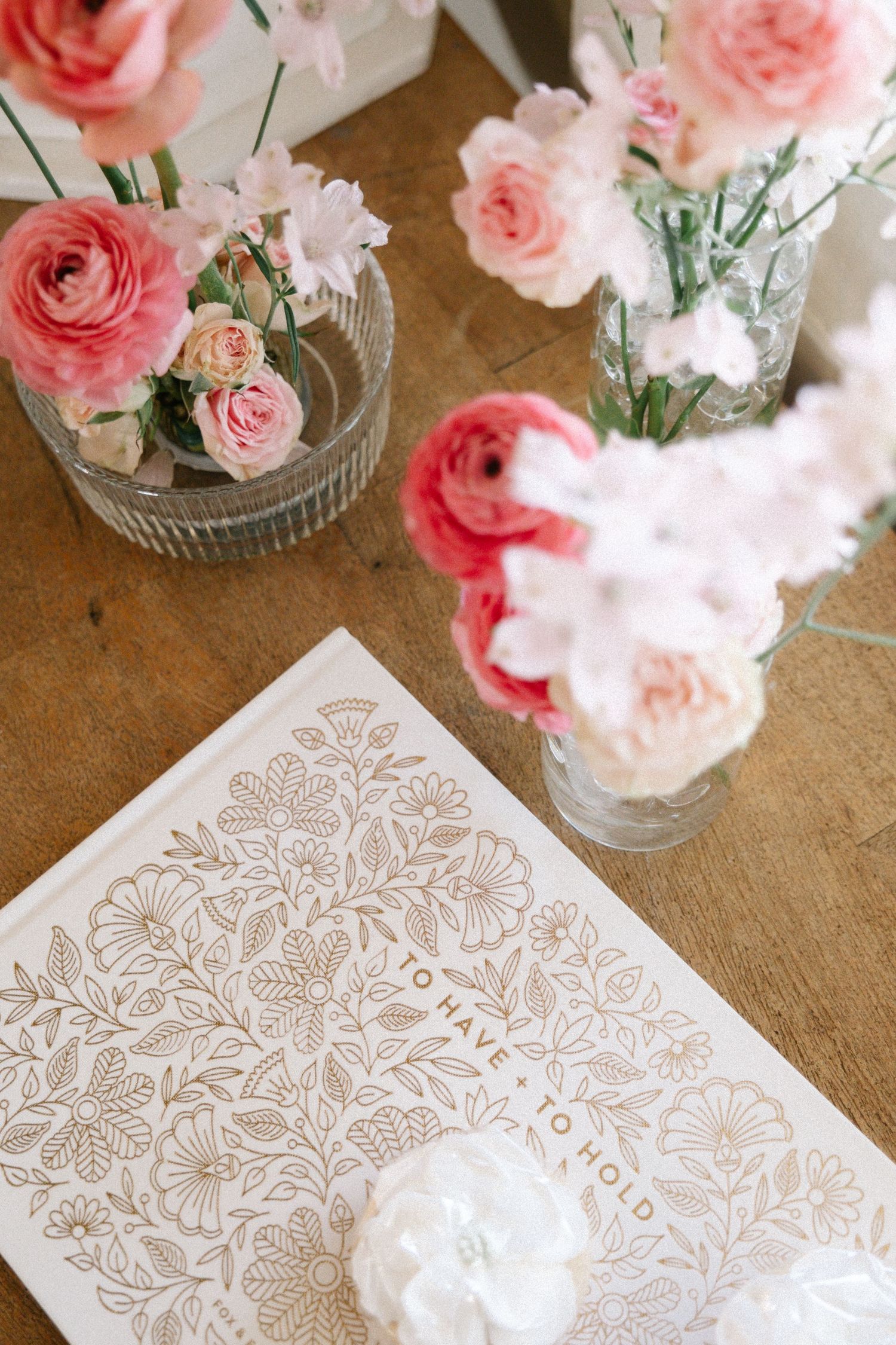 Pink roses in glass vases alongside delicate lace doilies create an elegant table setting arrangement.