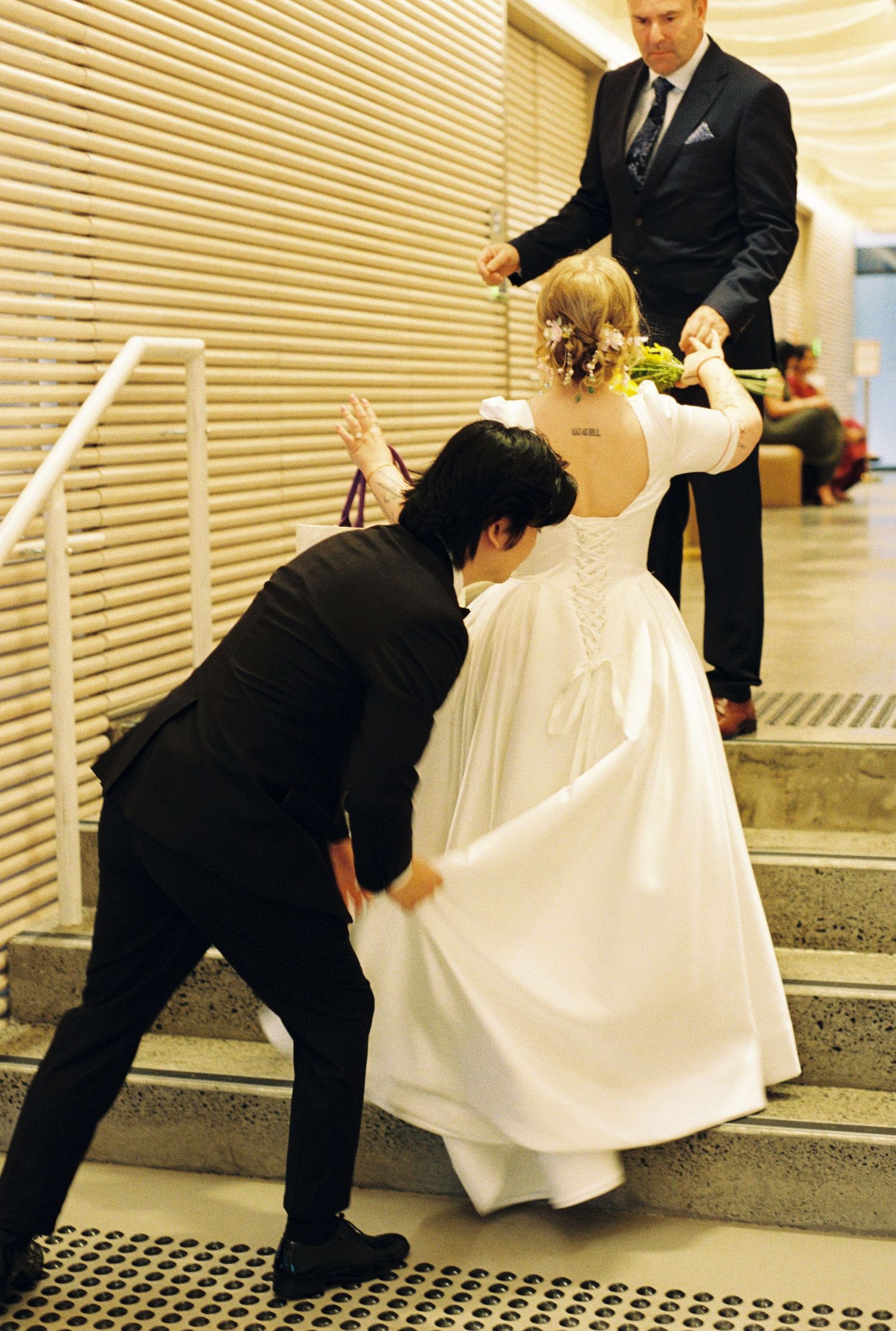 A sequence showing someone in a suit helping another person avoid a grate or drain on the floor in formal attire.