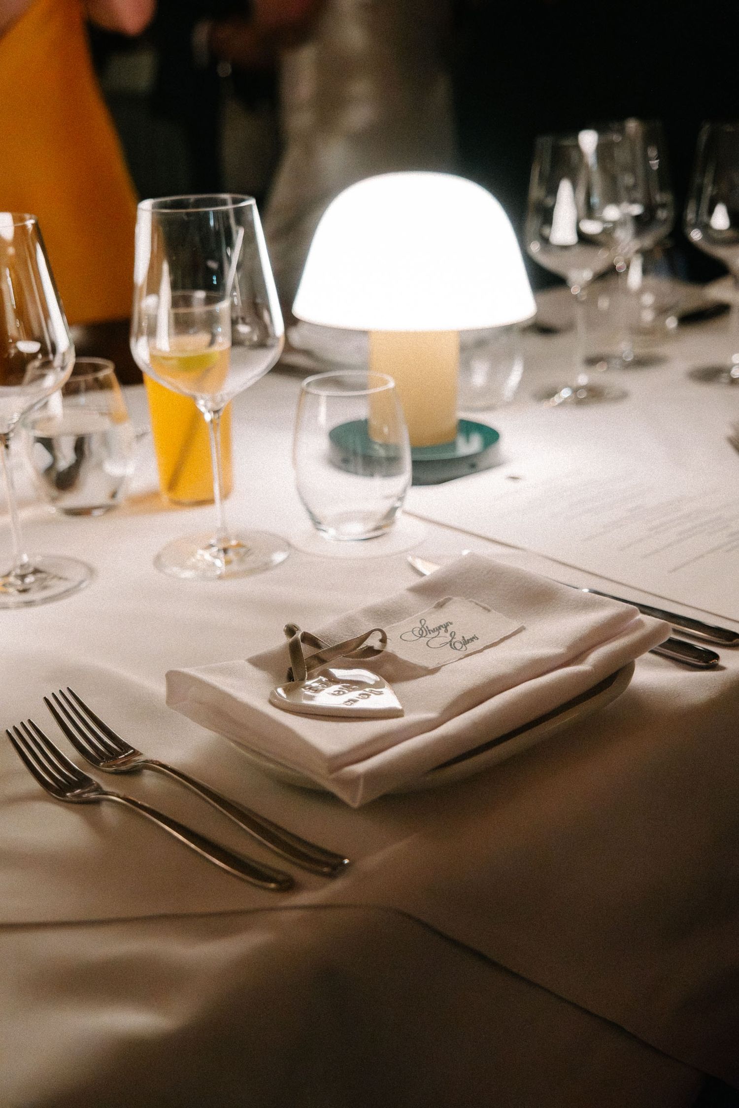 Elegant table settings with white linens, wine glasses, and silverware arranged in a fine dining restaurant.
