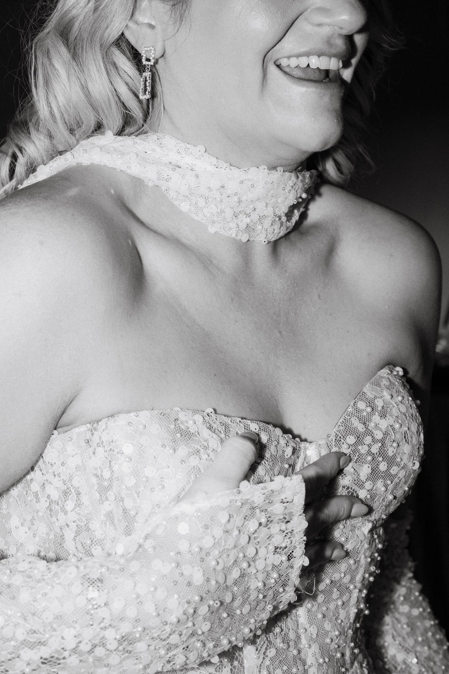 Close-up black and white photo of a bride wearing an ornate beaded wedding dress with strapless neckline.