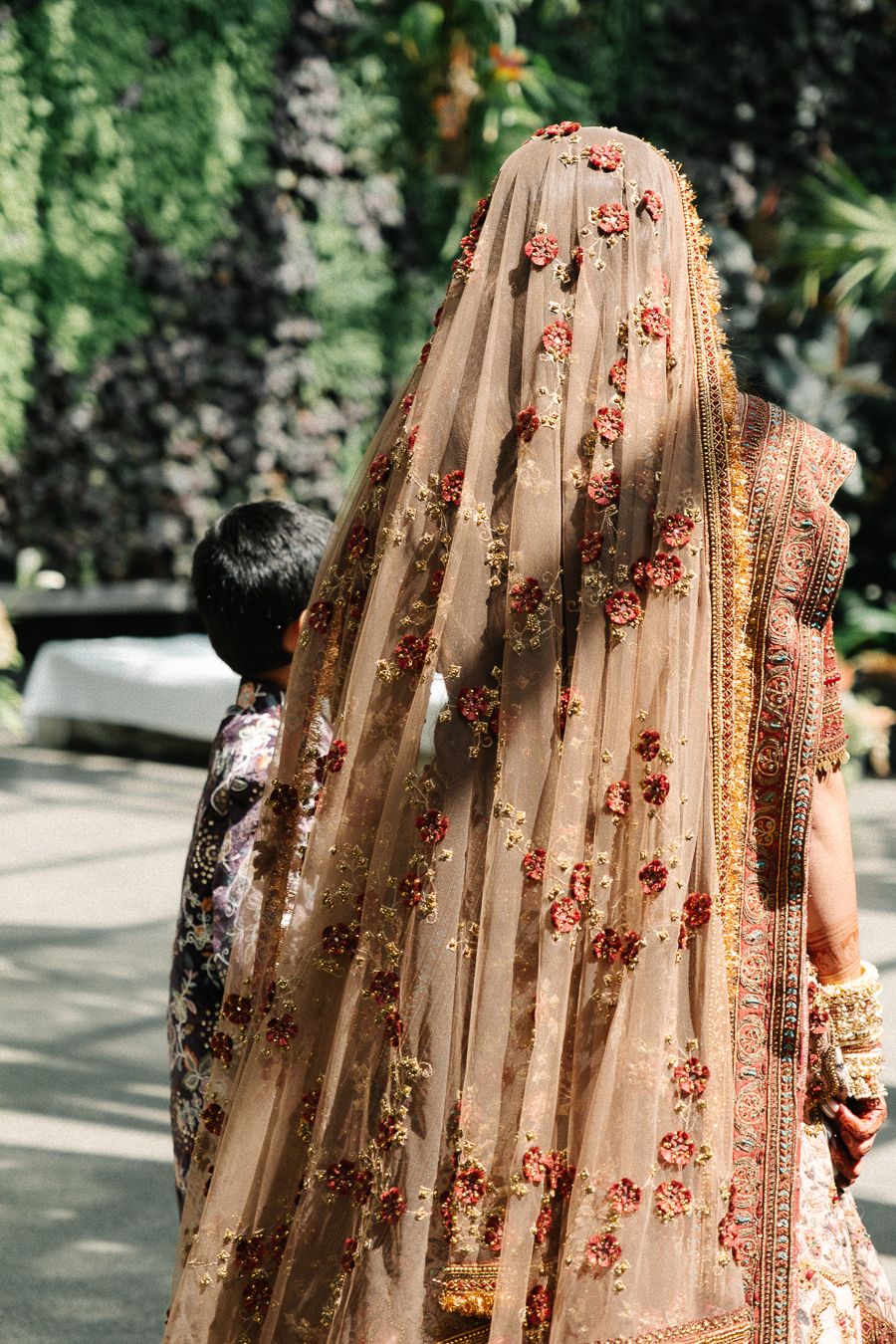 A traditional Indian wedding veil with delicate floral embroidery and gold details captured in natural outdoor lighting.