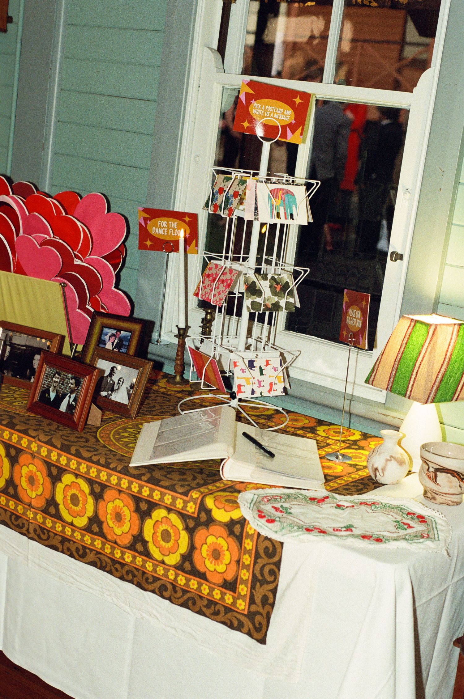 Wedding guest book table with decorative floral runner, photo frames, card display, and colorful stationery.