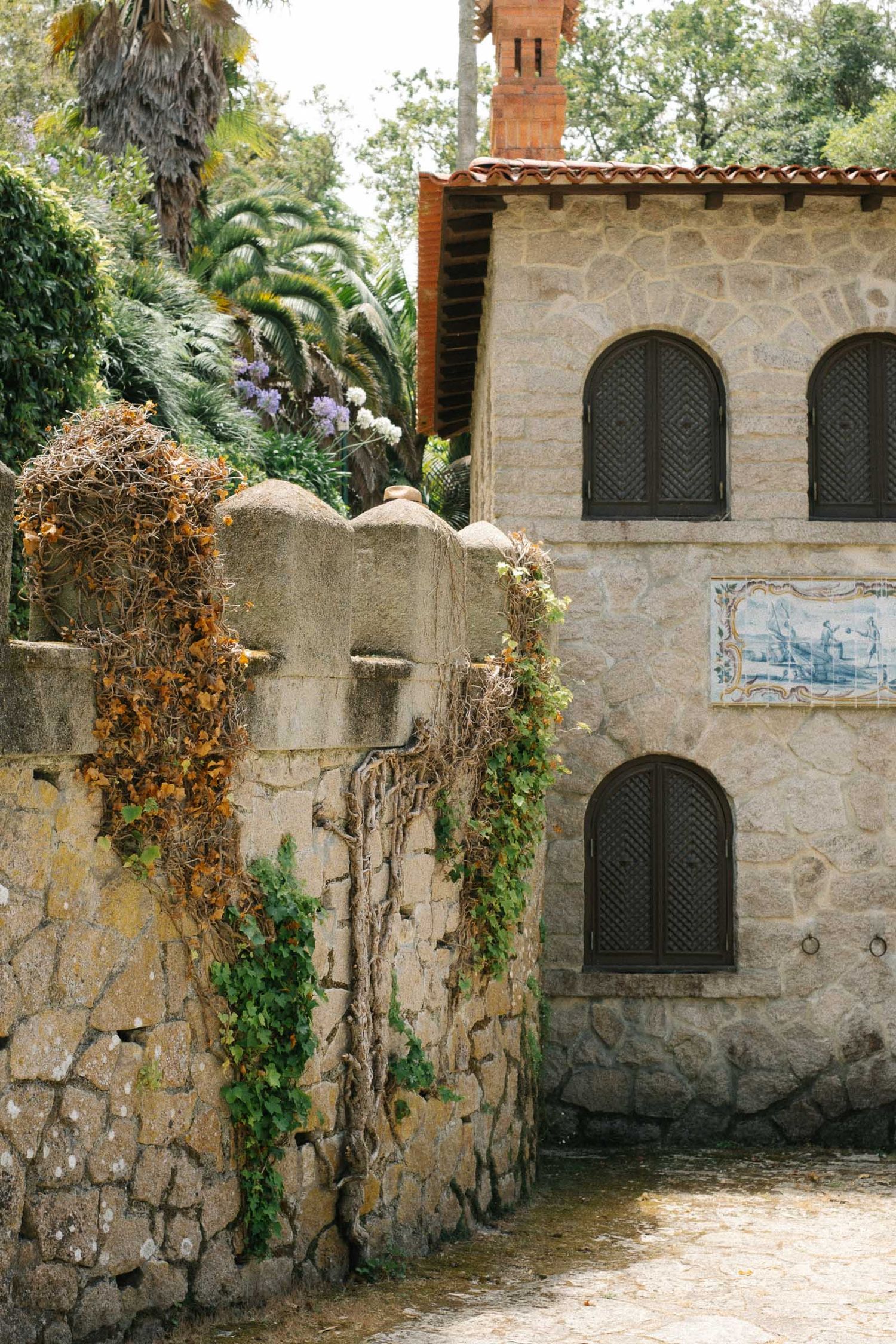 Stone wall with rustic arched windows and climbing vines creates a romantic garden setting.