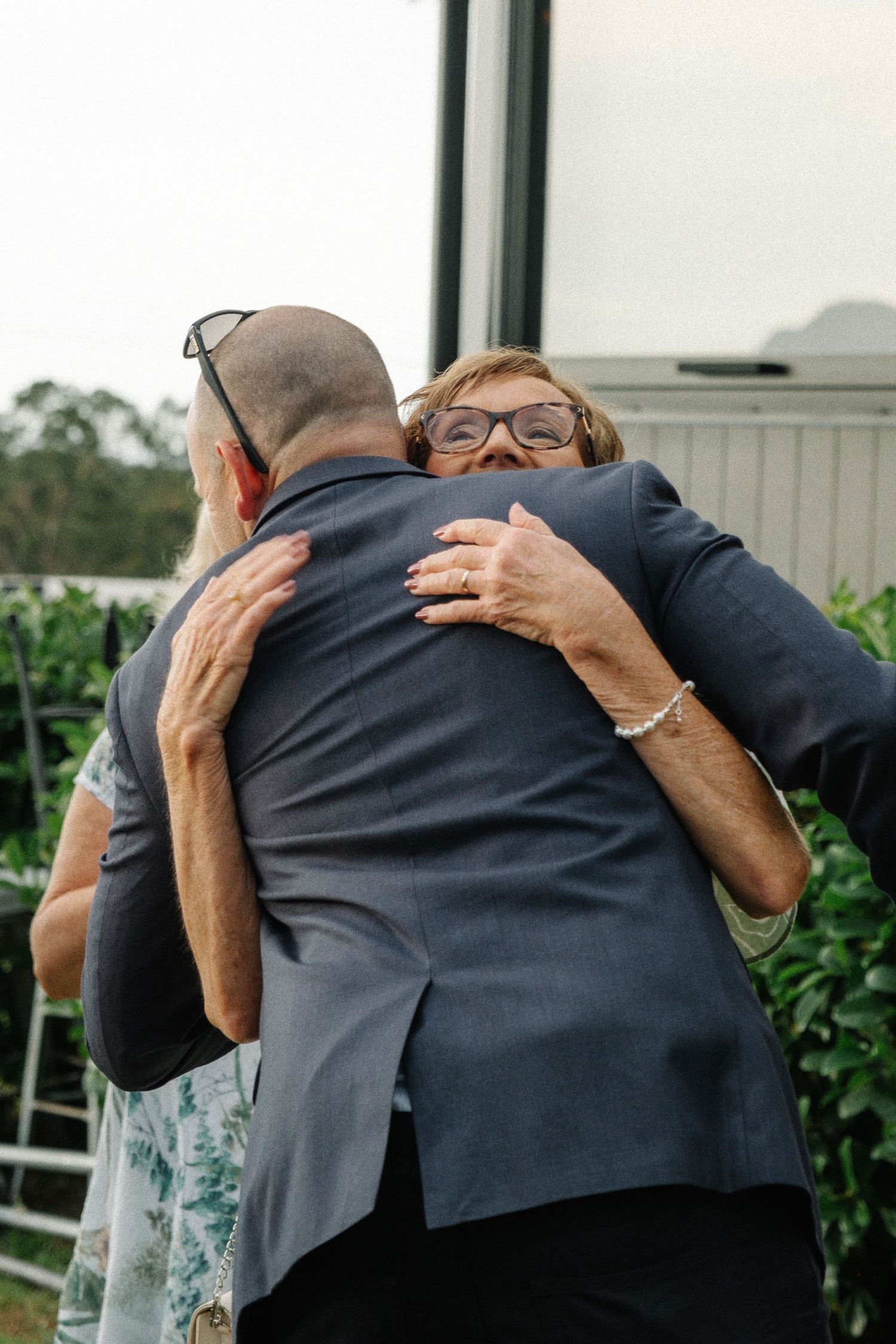 Three sequential photos show two people sharing an emotional embrace at an outdoor event.