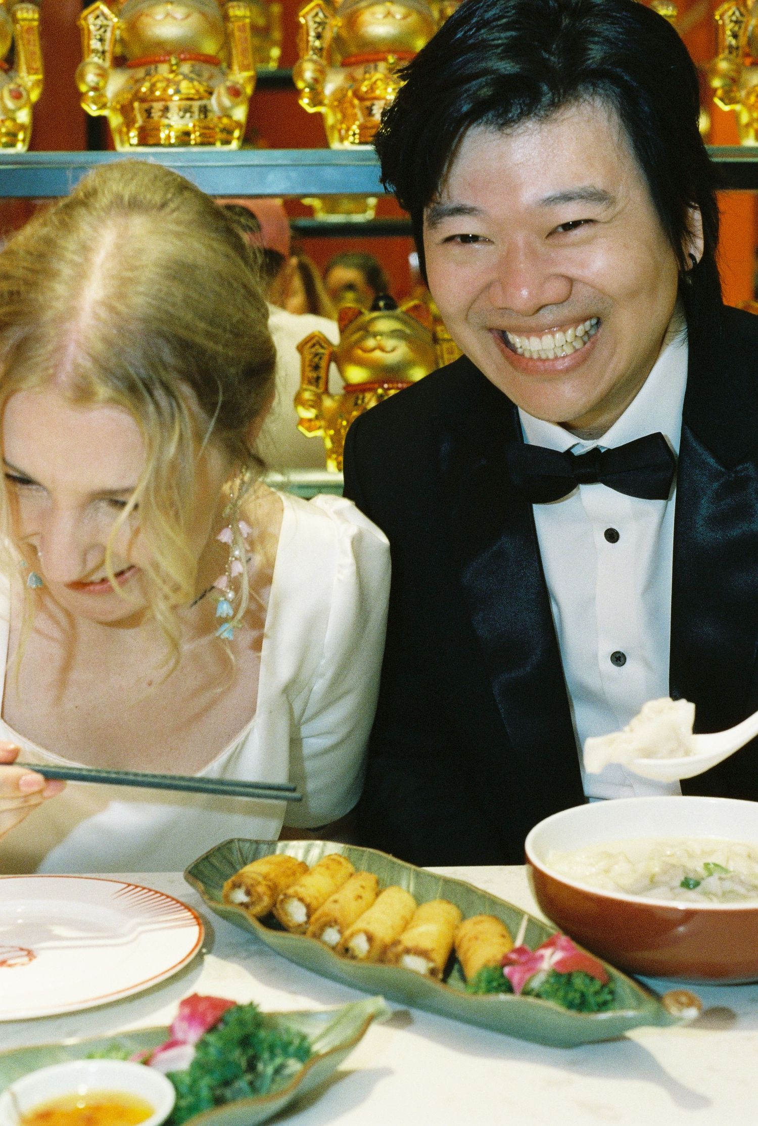 People enjoying a festive dinner gathering with plates of food and bright golden decor in the background.