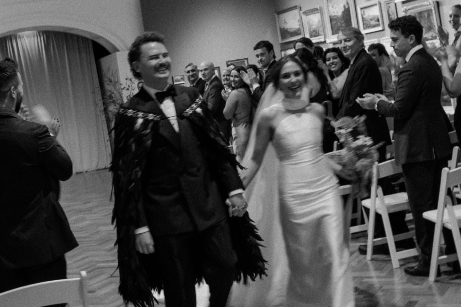 A joyful wedding celebration with guests watching a couple dancing during their first dance at an indoor reception.