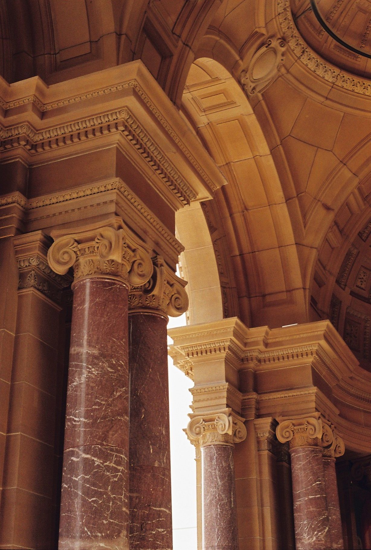 Ornate architectural detail of classical marble columns and Ionic capitals in a grand historic building interior.