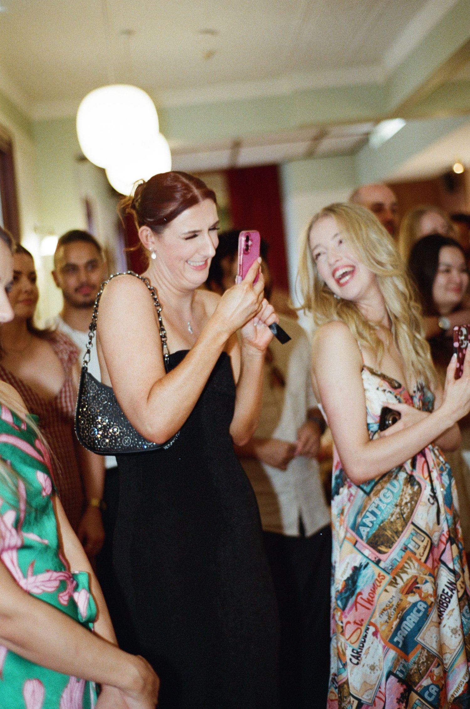 A group of wedding guests dance and laugh together during a celebration at an indoor venue.