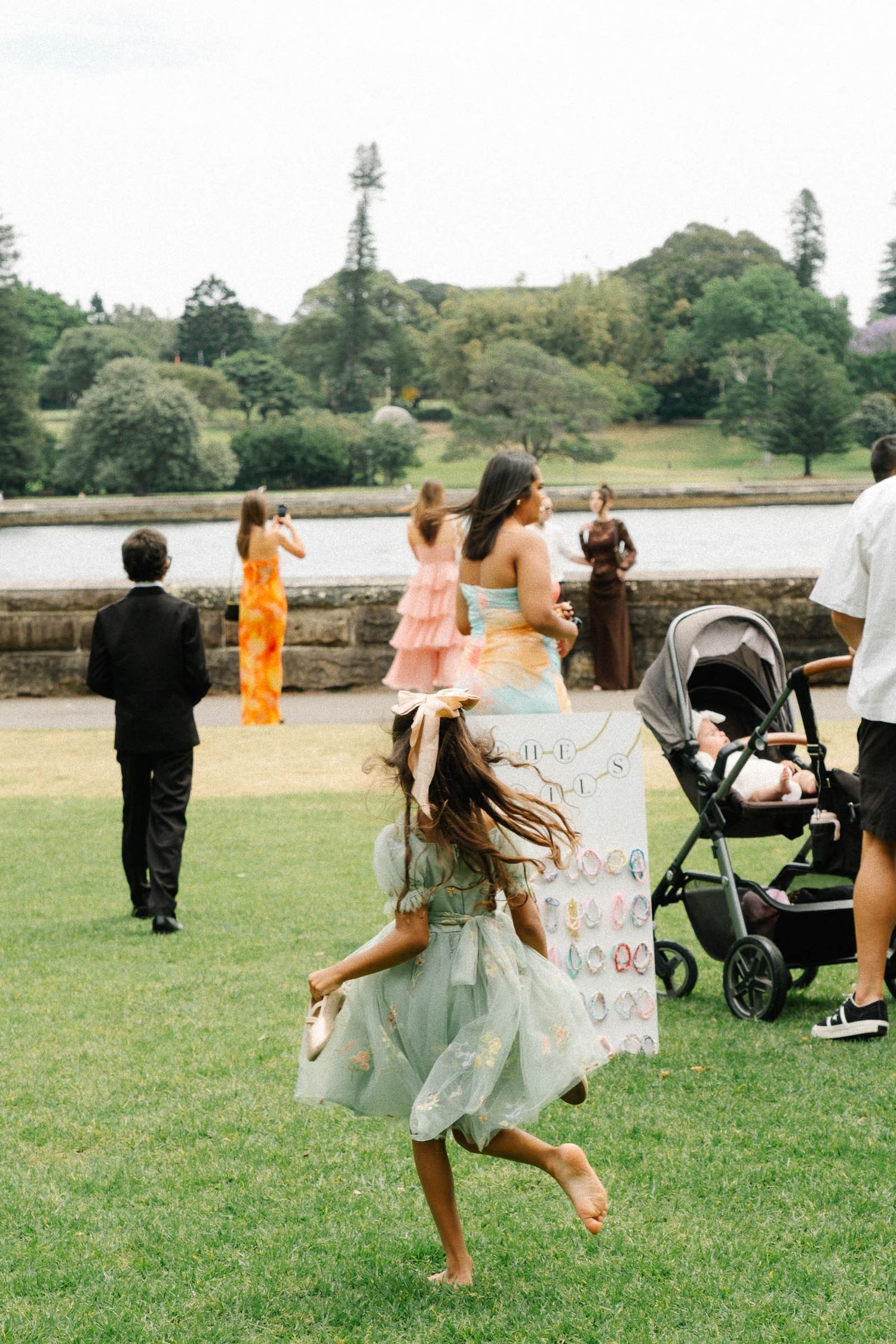 Wedding guests dance and celebrate on a grassy lawn during an outdoor reception at a scenic countryside venue.