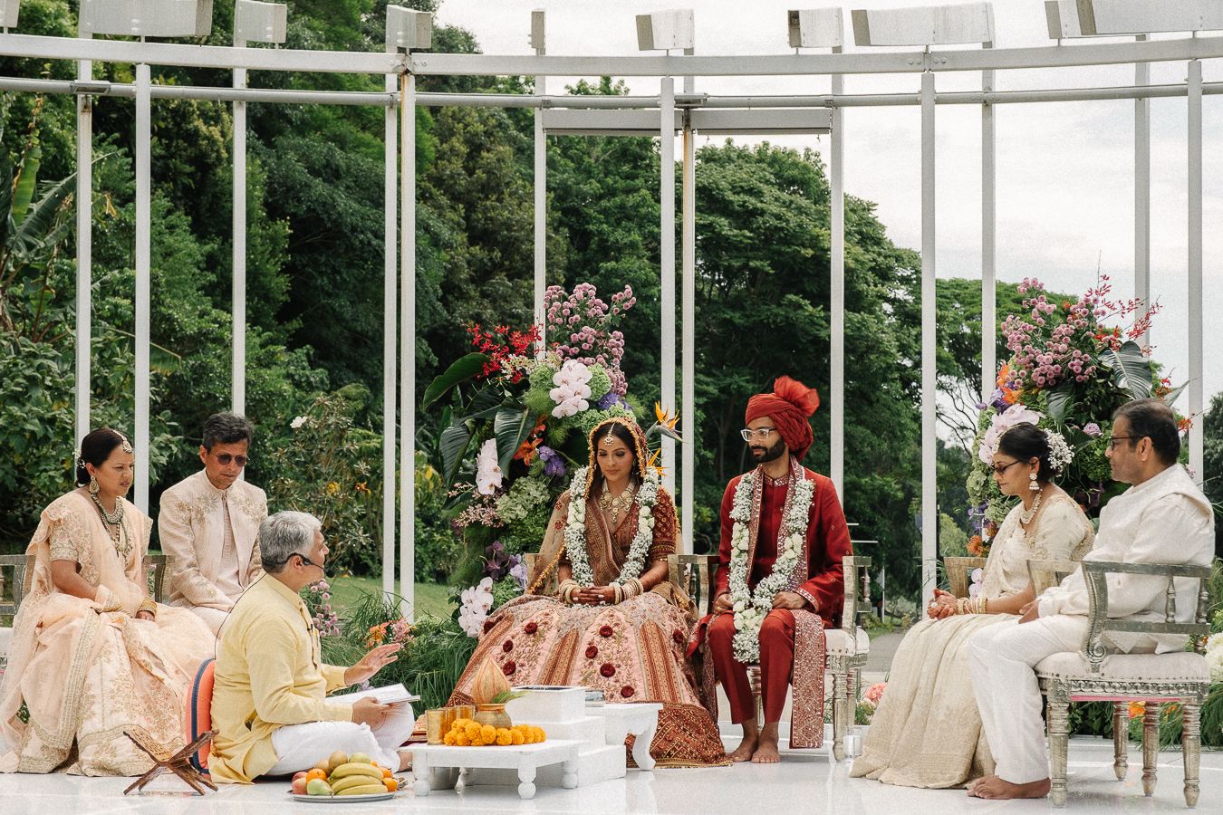 A panoramic view of a traditional Indian wedding ceremony with guests seated in a bright outdoor venue.
