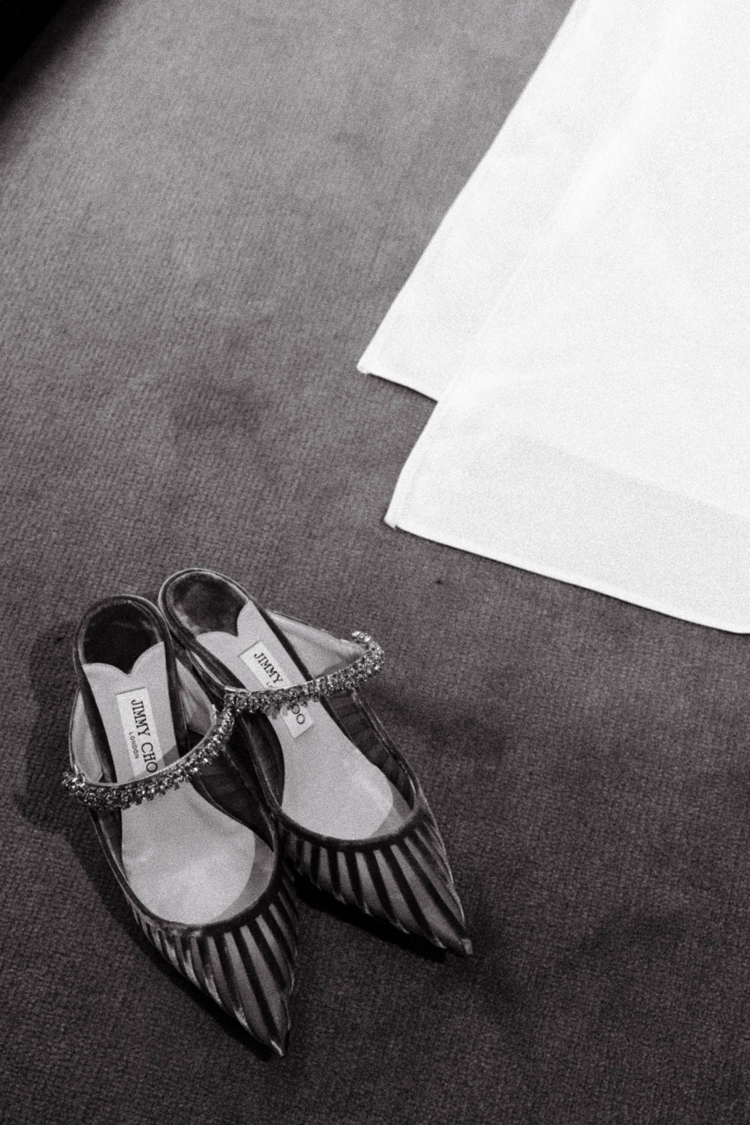A sequence of black and white photos showing a pair of striped high heel shoes on dark carpet.