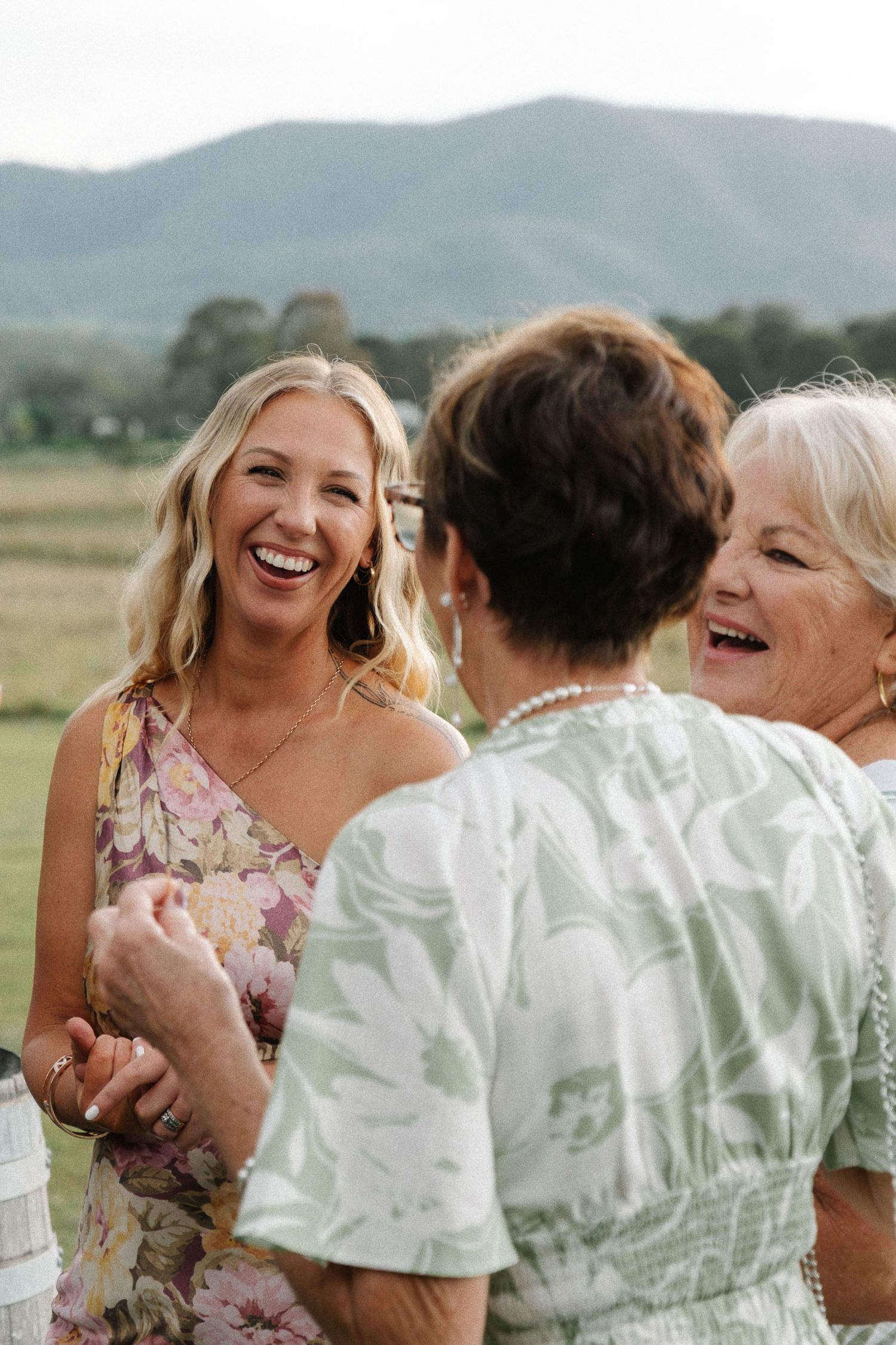 Friends enjoying a candid moment of laughter together against a scenic mountain landscape.
