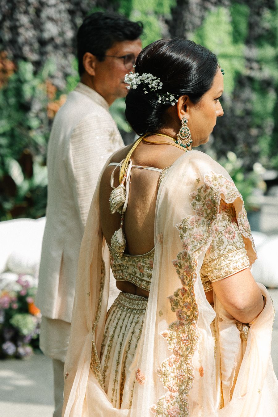 Elegant wedding party members wearing traditional South Asian attire with intricate gold embroidery and flowing fabrics.