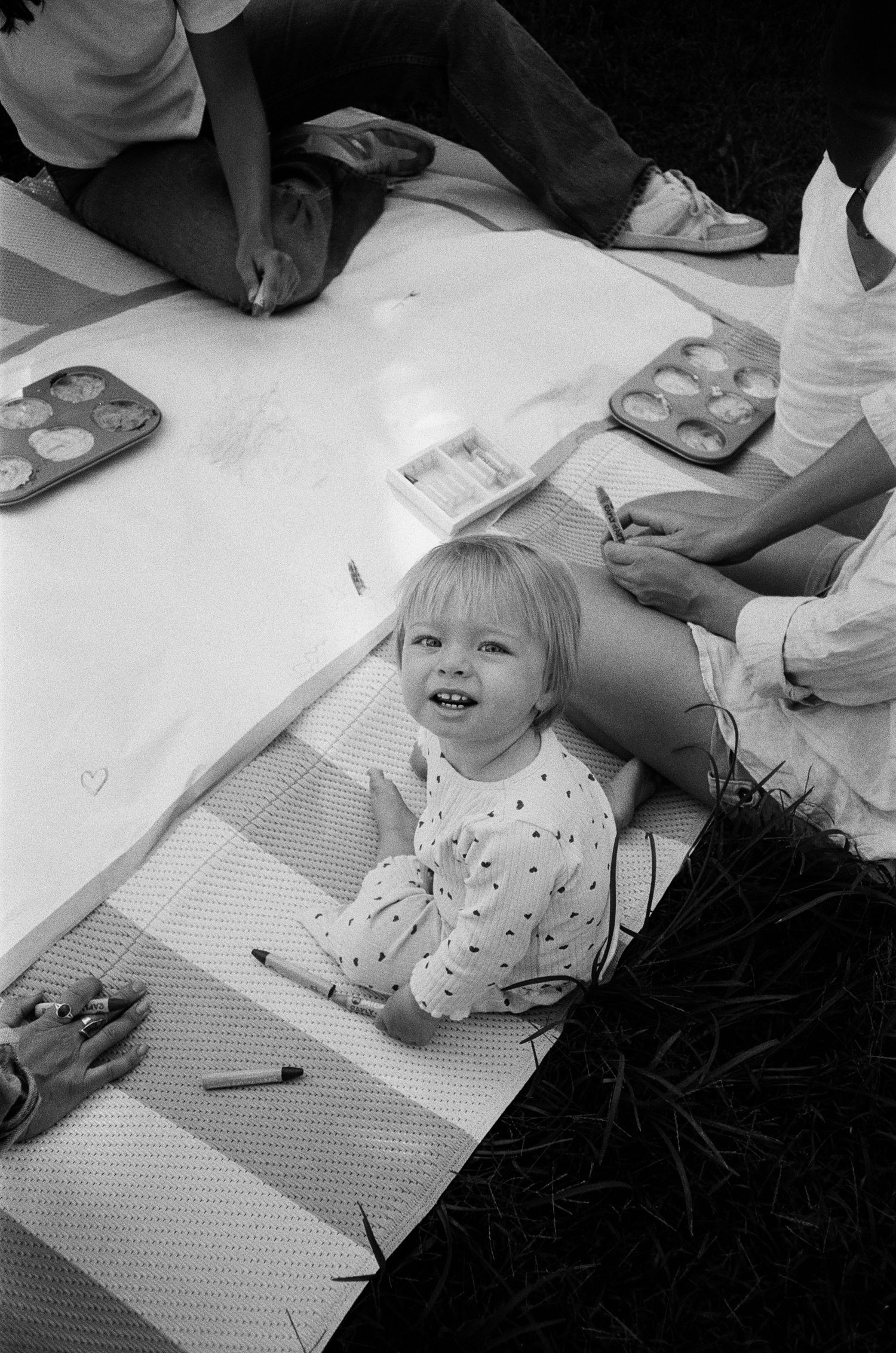 A sequence of black and white photos showing a child lying on paper and drawing during an art activity.