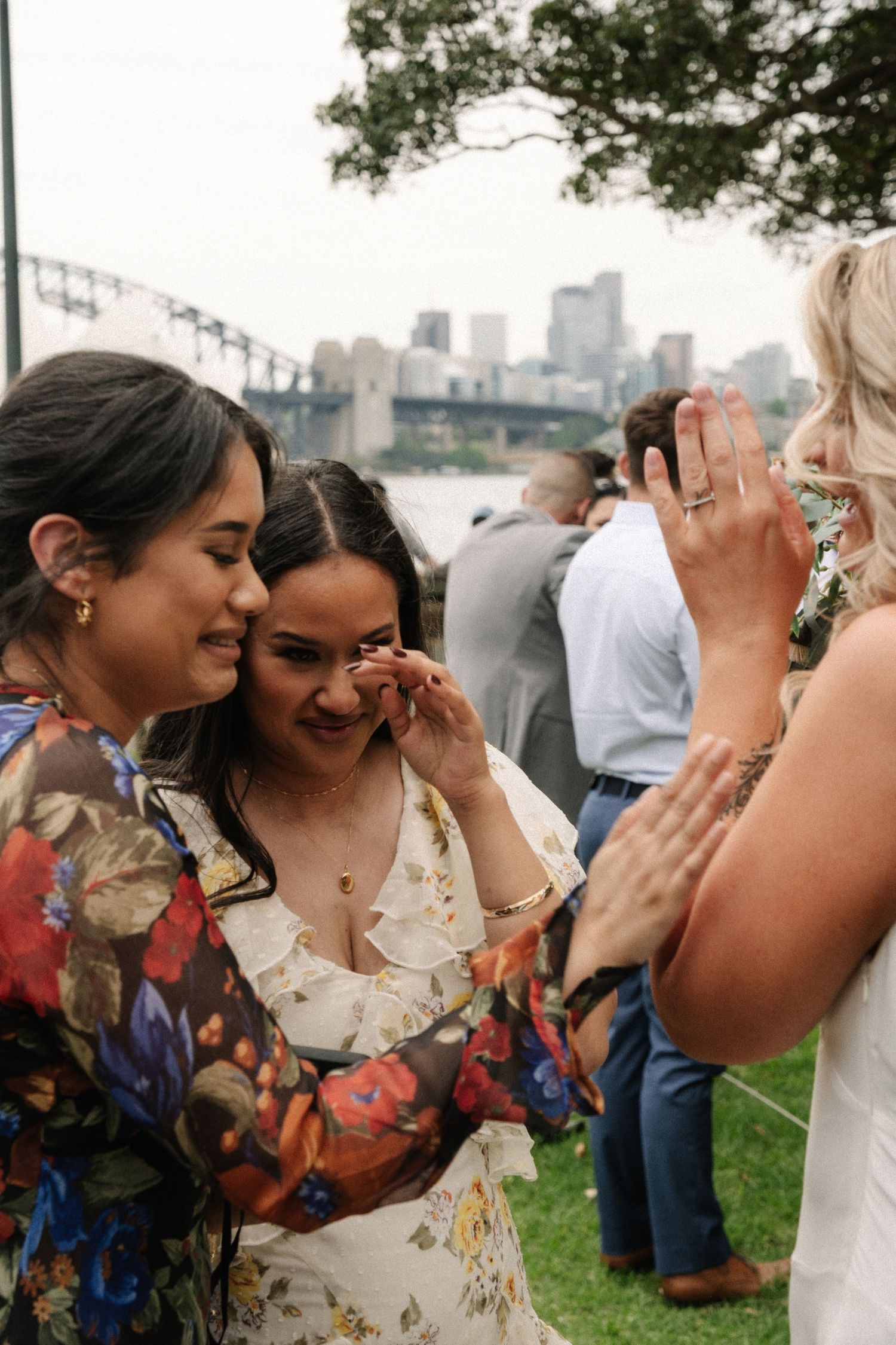 Two people share an intimate emotional moment while laughing together at an outdoor gathering.