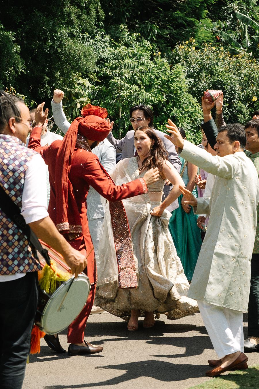 A group of people in traditional Indian attire dancing and celebrating at an outdoor cultural event.