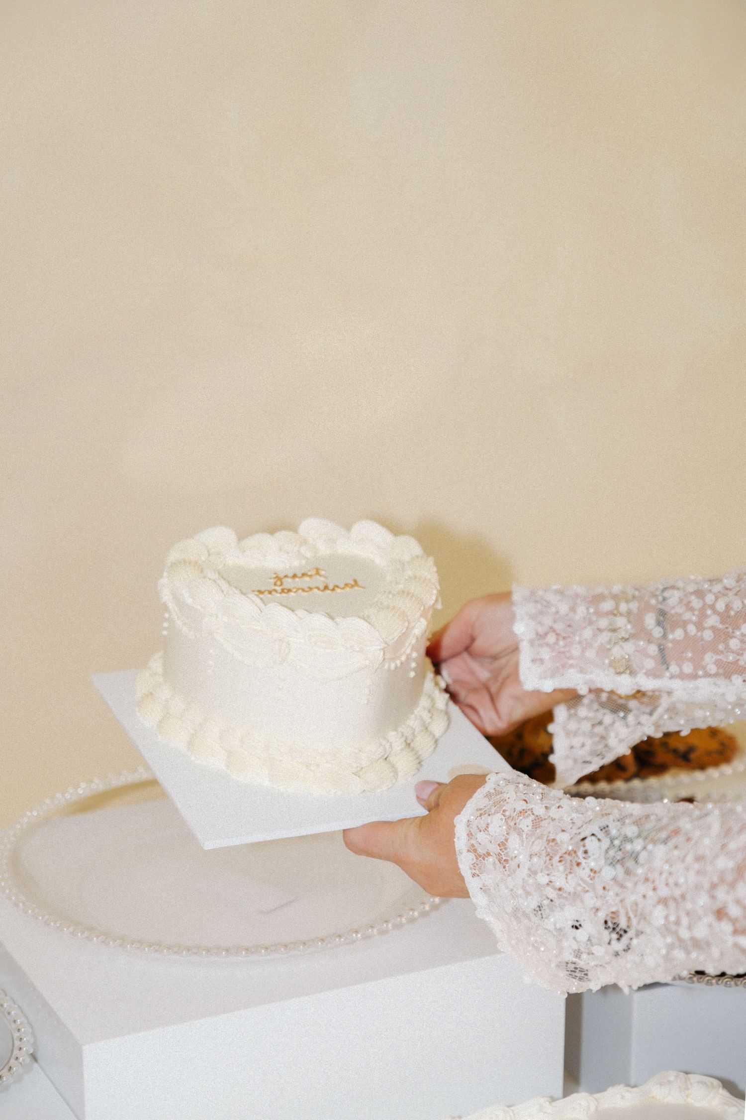 Series of hands carefully arranging delicate white lace wedding accessories on a light beige surface.