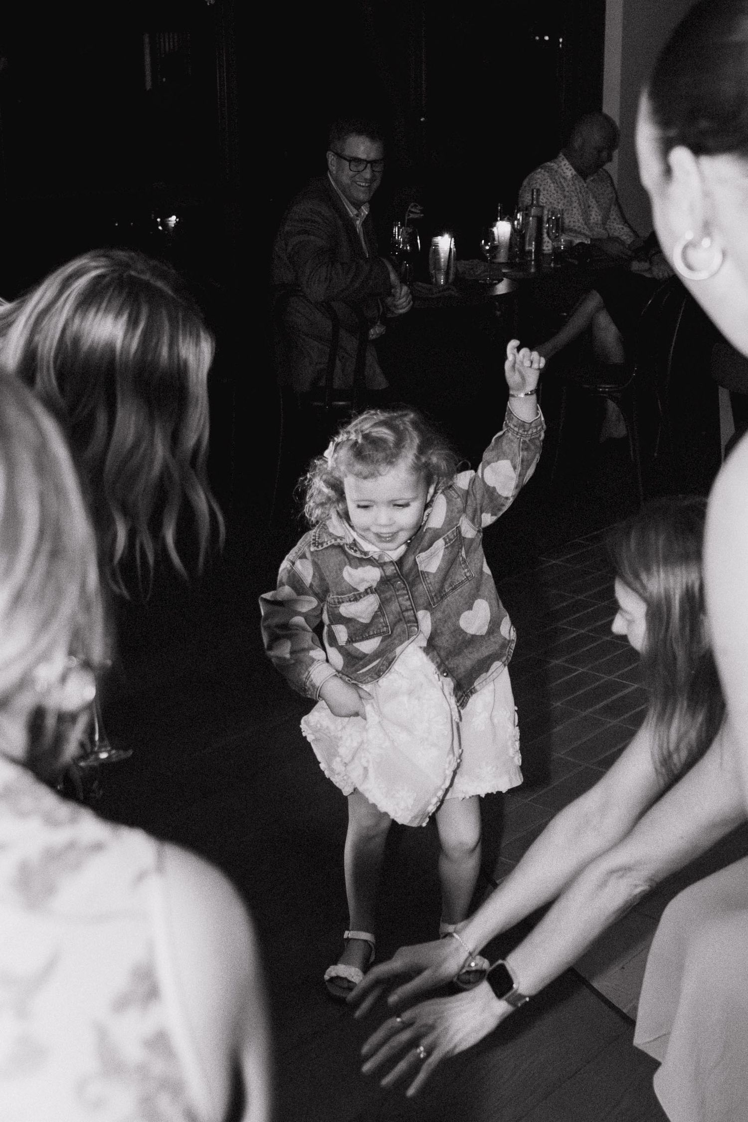 Children dancing and playing together on a dark dance floor at an evening celebration.