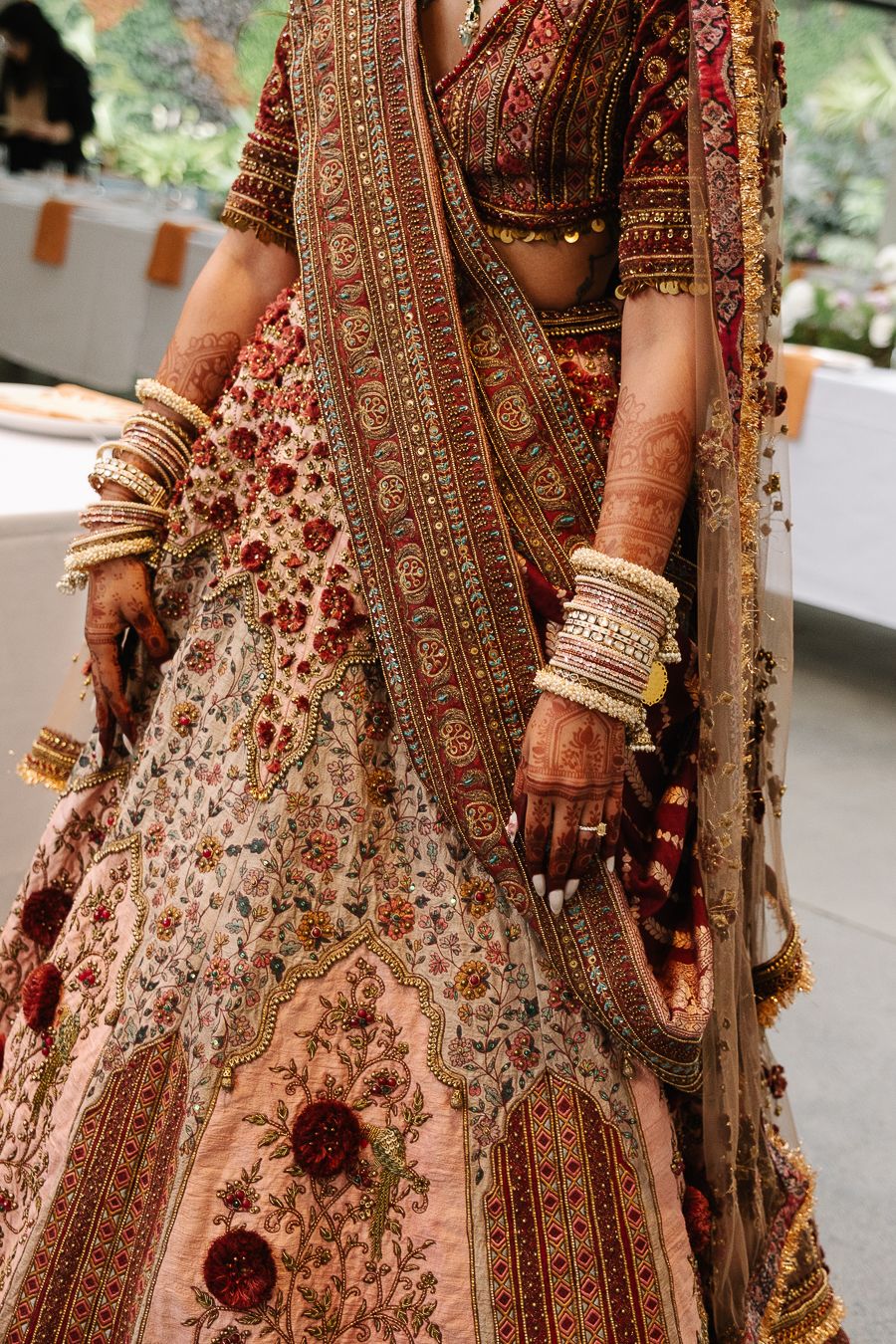 Ornate Indian bridal lehenga with intricate embroidery, bangles and mehndi designs showcasing traditional wedding attire.