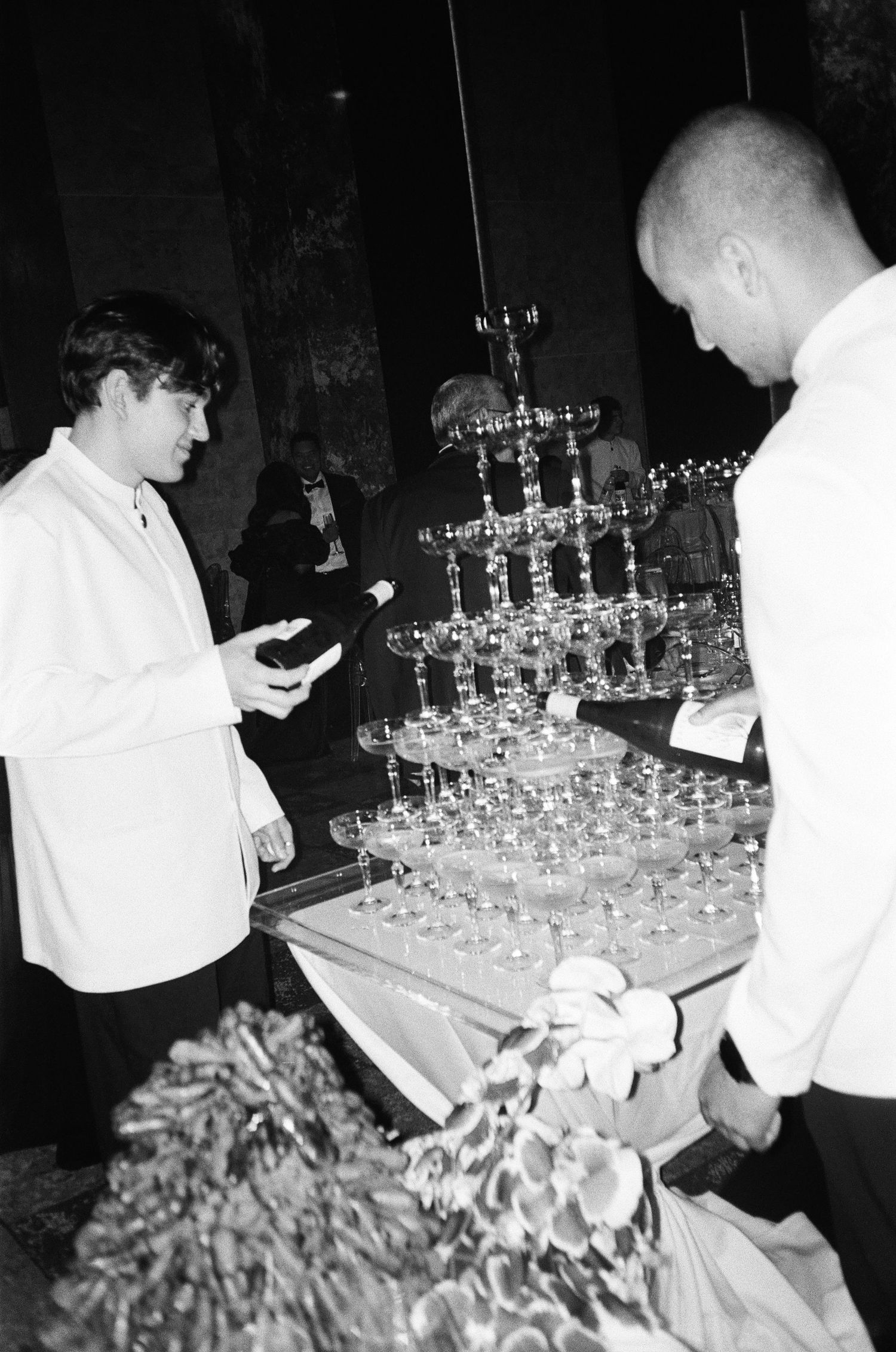 Black and white photo of waiters preparing champagne glasses for a formal event.