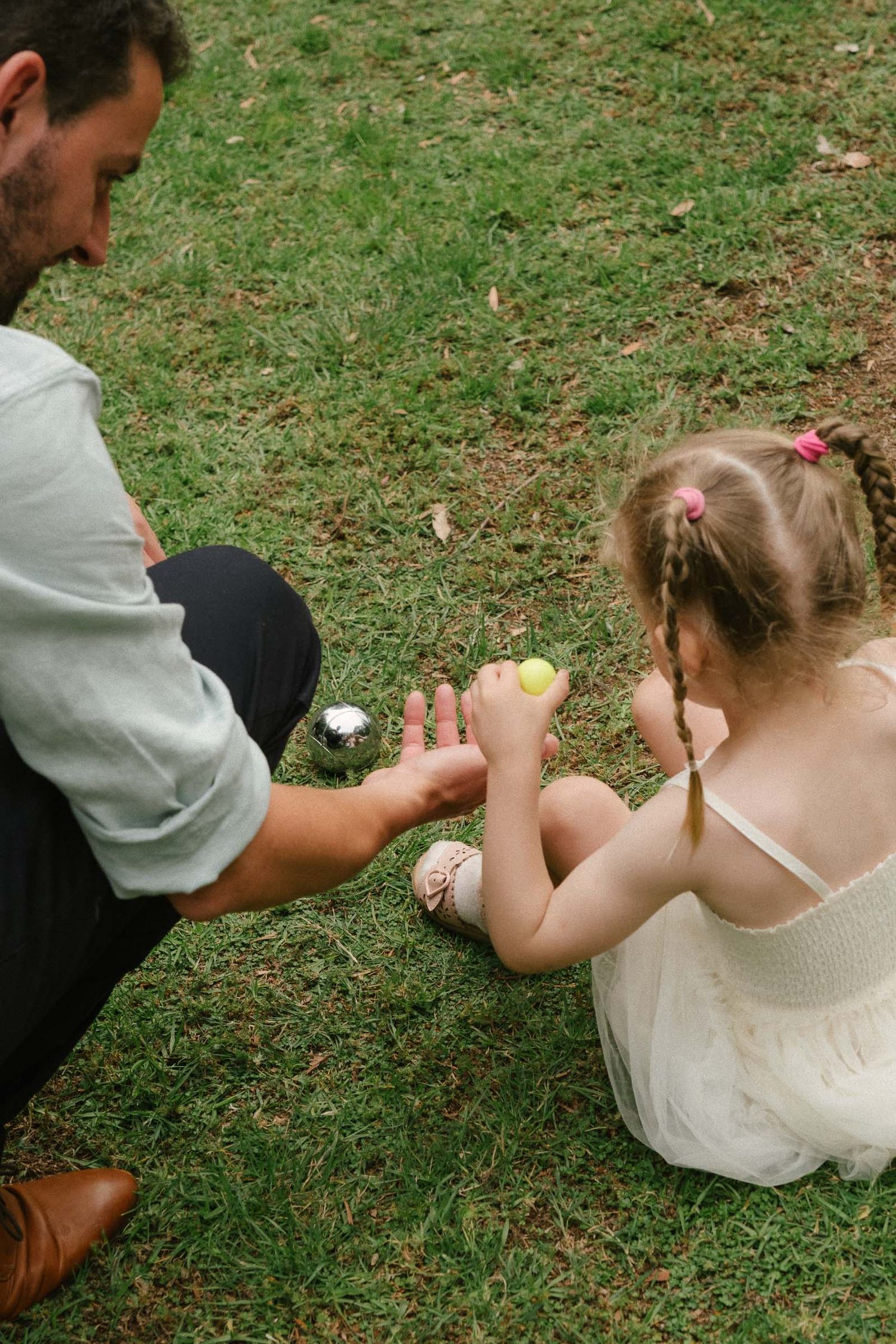 A sequence of four photos showing a proposal moment on grass with a baseball being opened to reveal a ring.