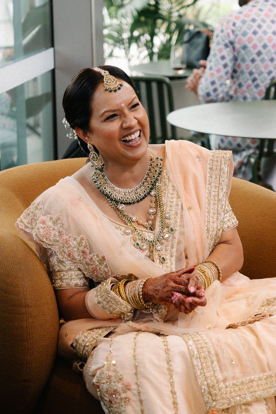A series of candid moments showing someone wearing a peach-colored traditional Indian wedding outfit with elegant jewelry.