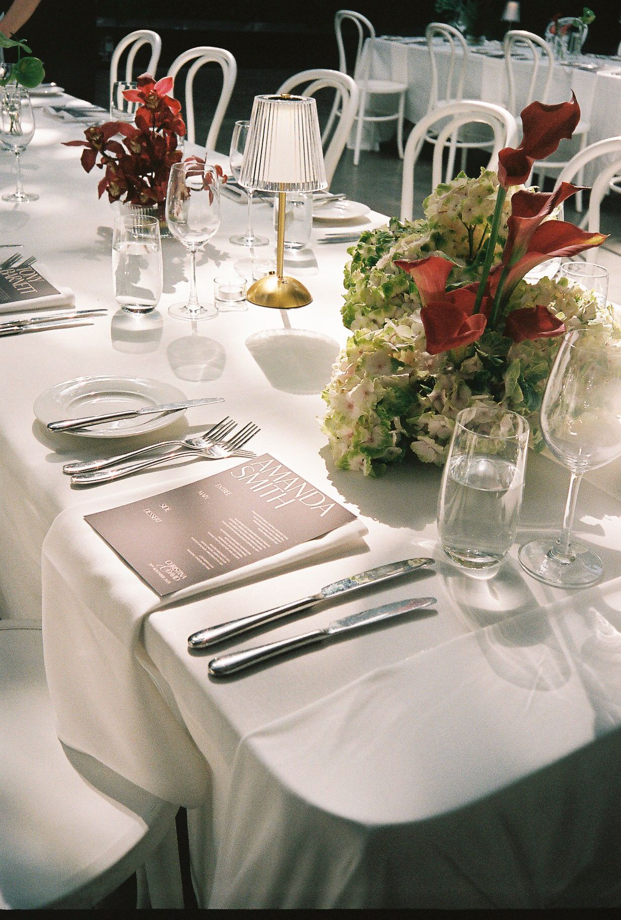 Elegant table settings with white linens, silverware, and floral centerpieces at a formal dining event.