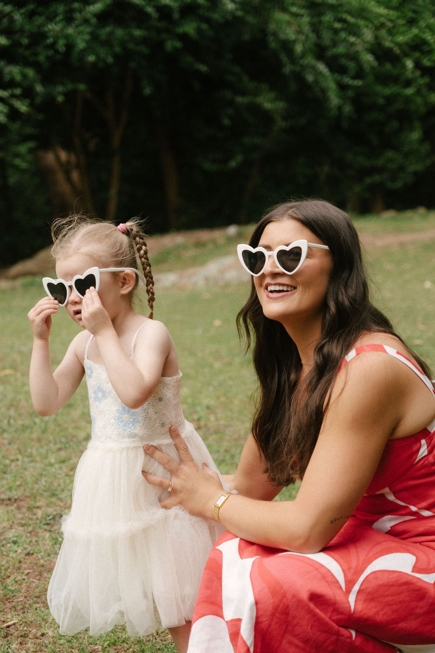 A heartwarming series of photos showing a parent and child in matching heart-shaped sunglasses sharing joyful moments outdoors.