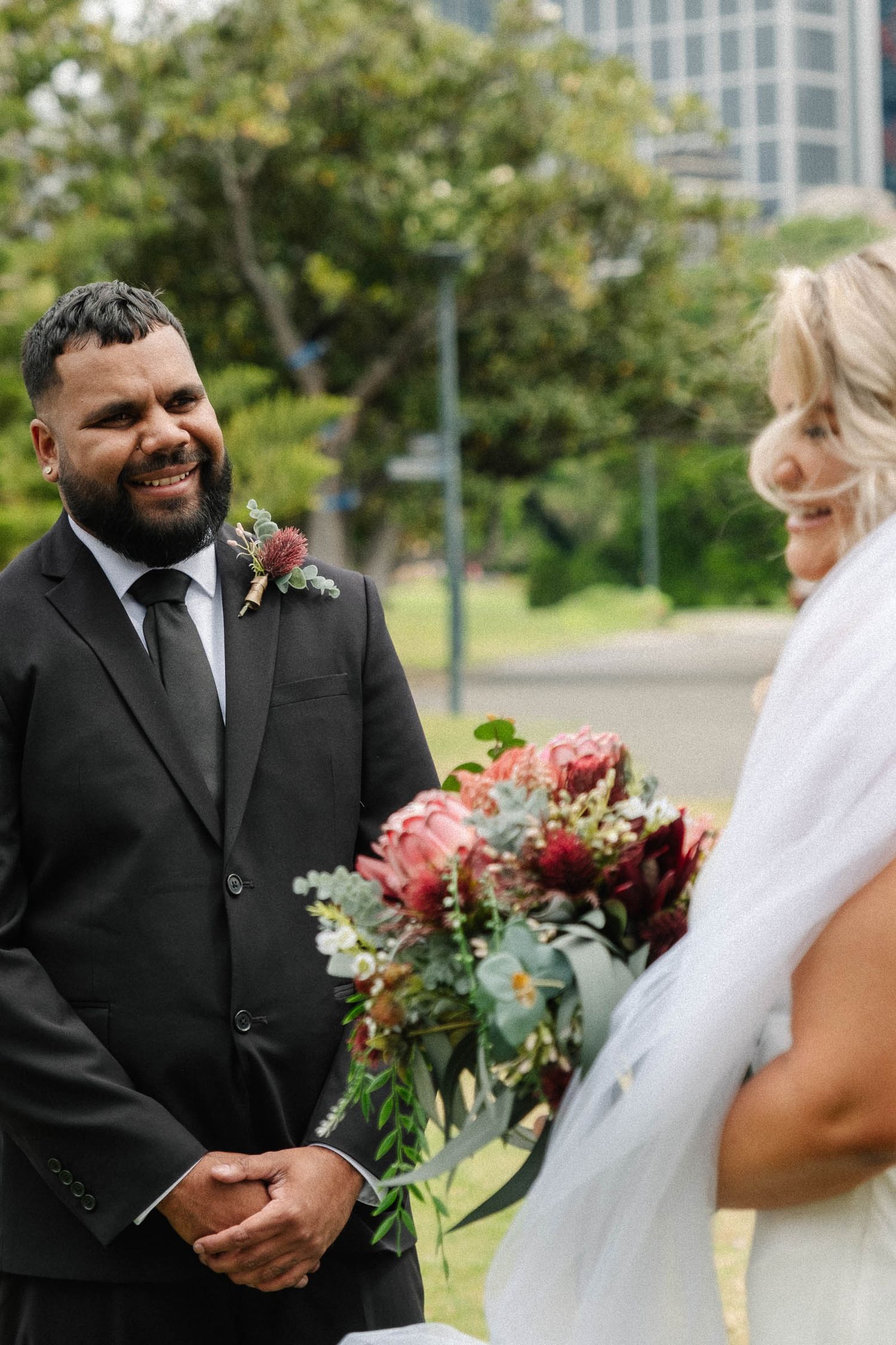 A candid wedding moment captured outdoors with a beautiful bouquet of pink flowers and eucalyptus.