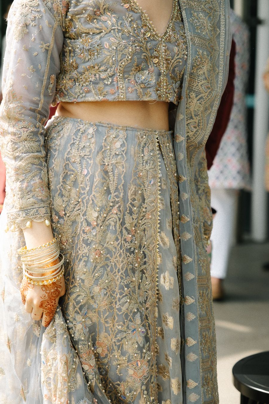 Close-up detail of an elegant silver and grey embroidered formal dress with intricate beadwork and delicate lace patterns.