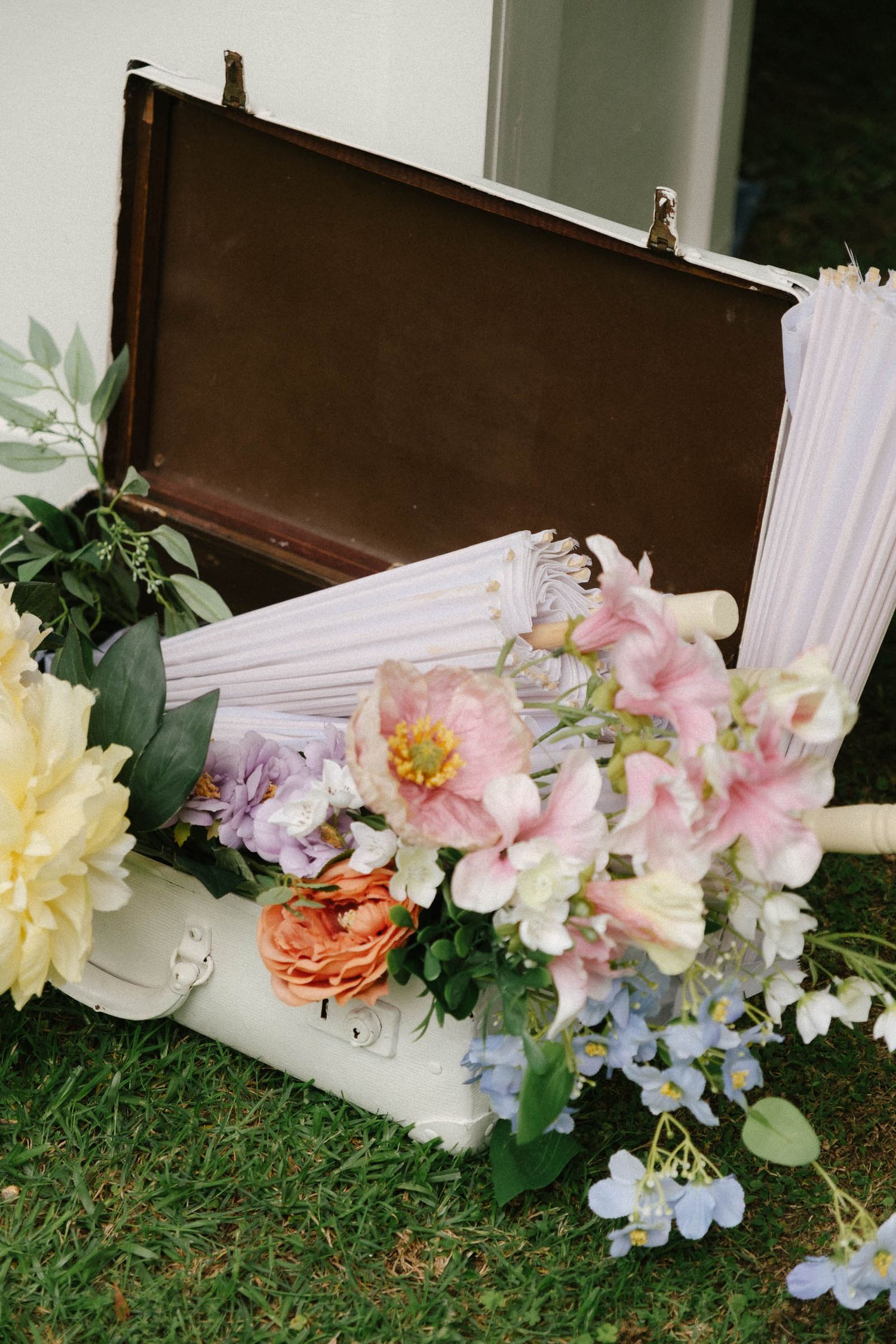 A row of pink and white flowers arranged along the base of a window with grass visible in the foreground.