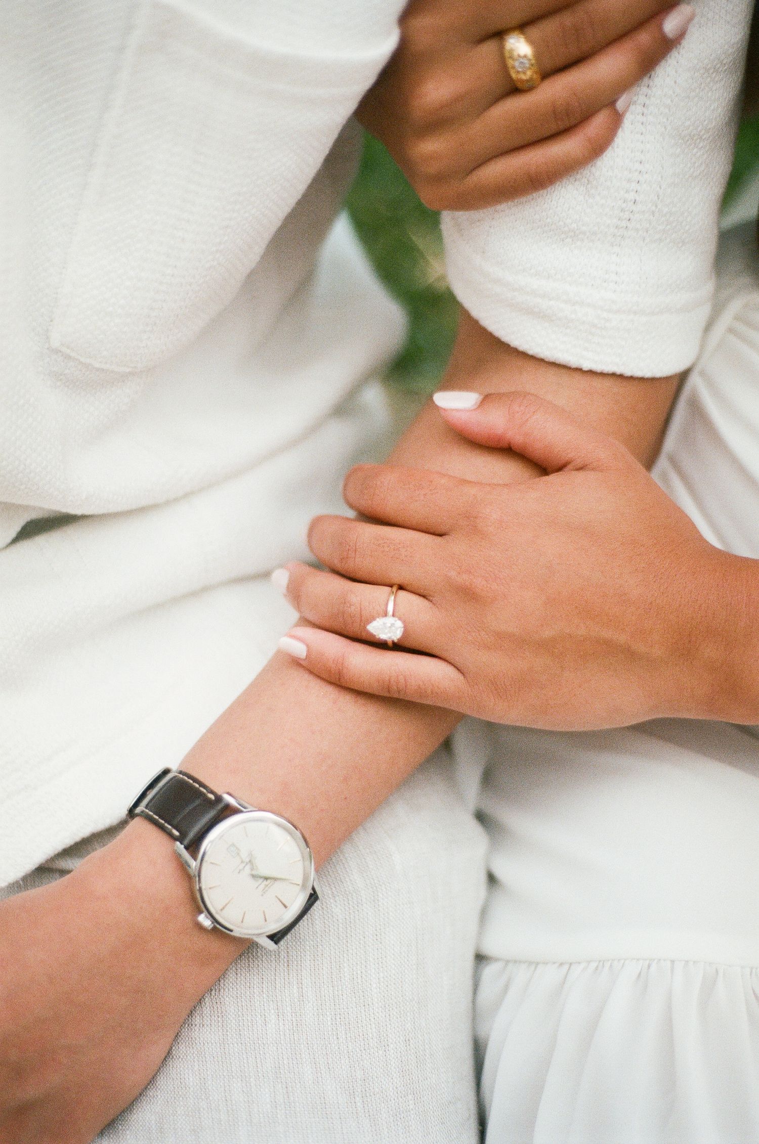 Close-up view of hands wearing gold rings against white linen fabric, showcasing minimalist jewelry styling.