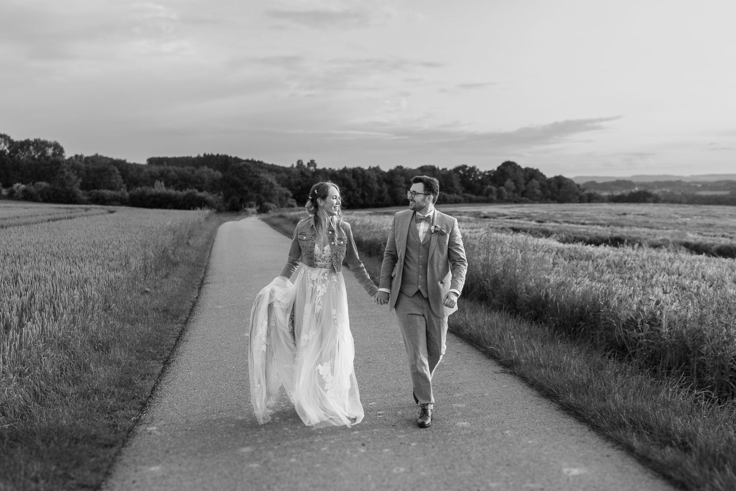 Couple walking along a scenic countryside path through golden wheat fields on a summer day.