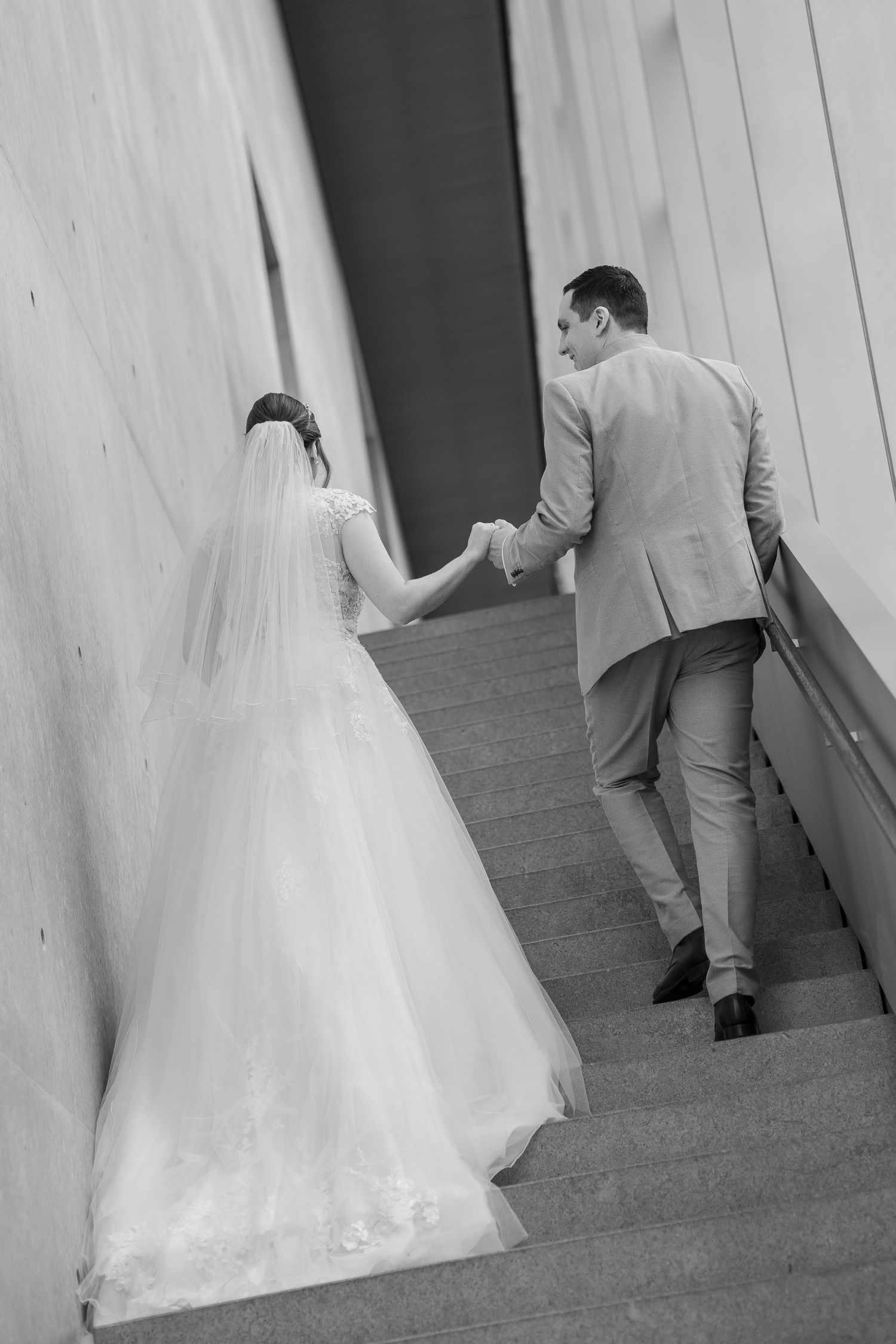 Black and white sequence of a bride and groom walking up stairs in formal wedding attire.