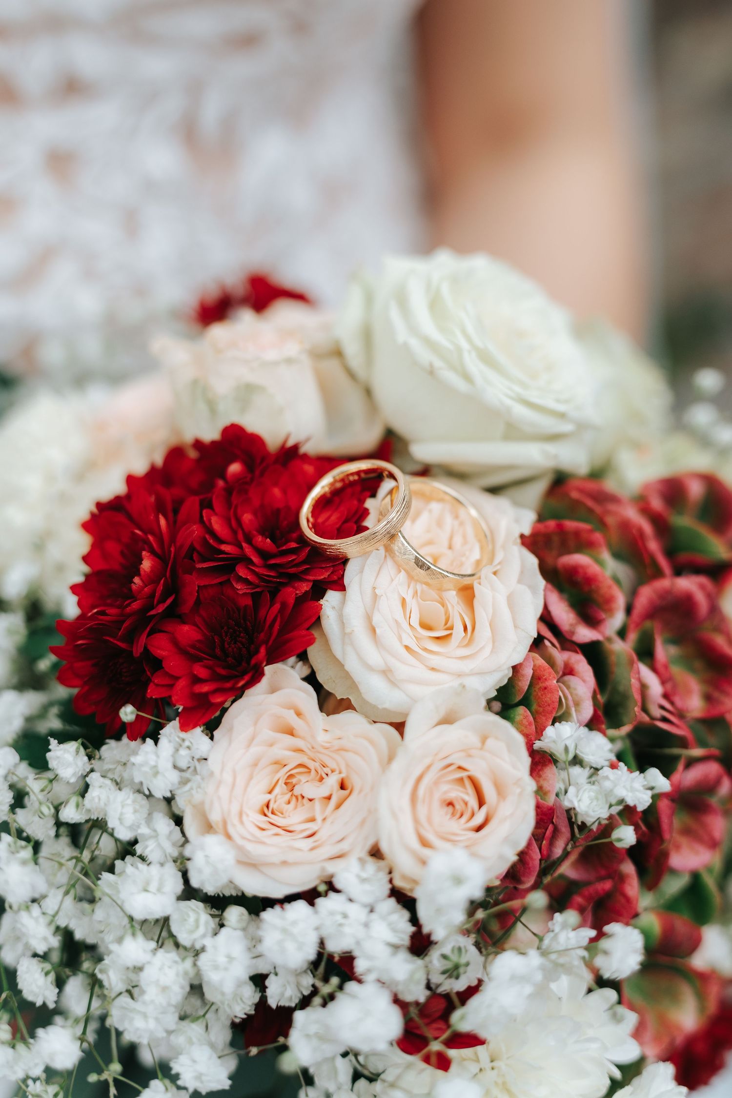 Elegant floral arrangement featuring peach roses, deep red carnations and delicate white baby's breath flowers.