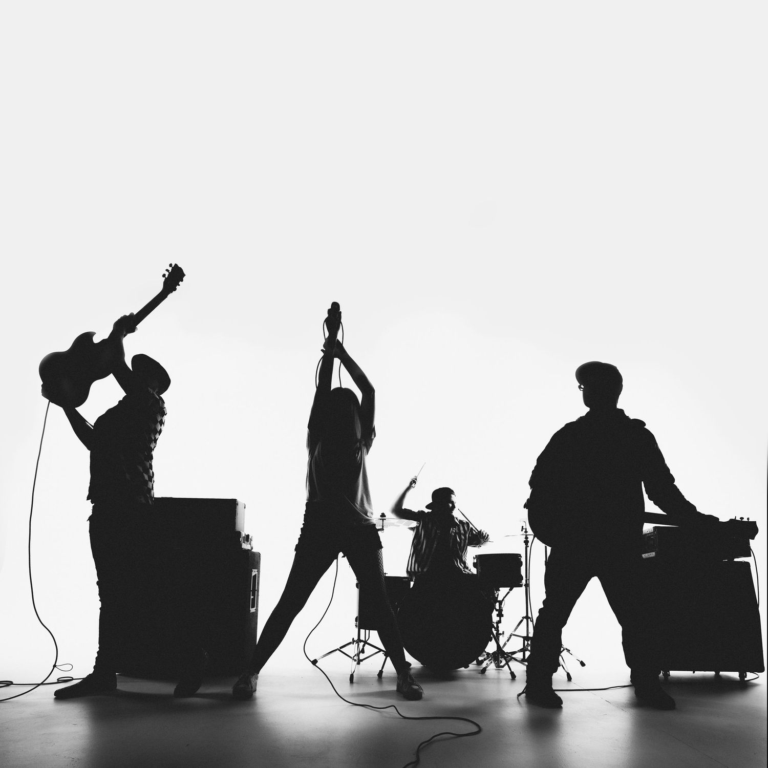 Silhouetted musicians performing on stage with instruments and equipment visible in dramatic black and white.