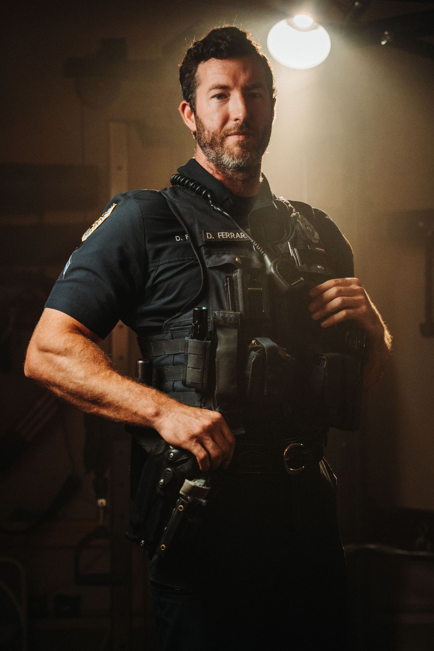 A tactical operator in dark clothing holds a weapon in a dimly lit indoor setting with dramatic lighting effects.